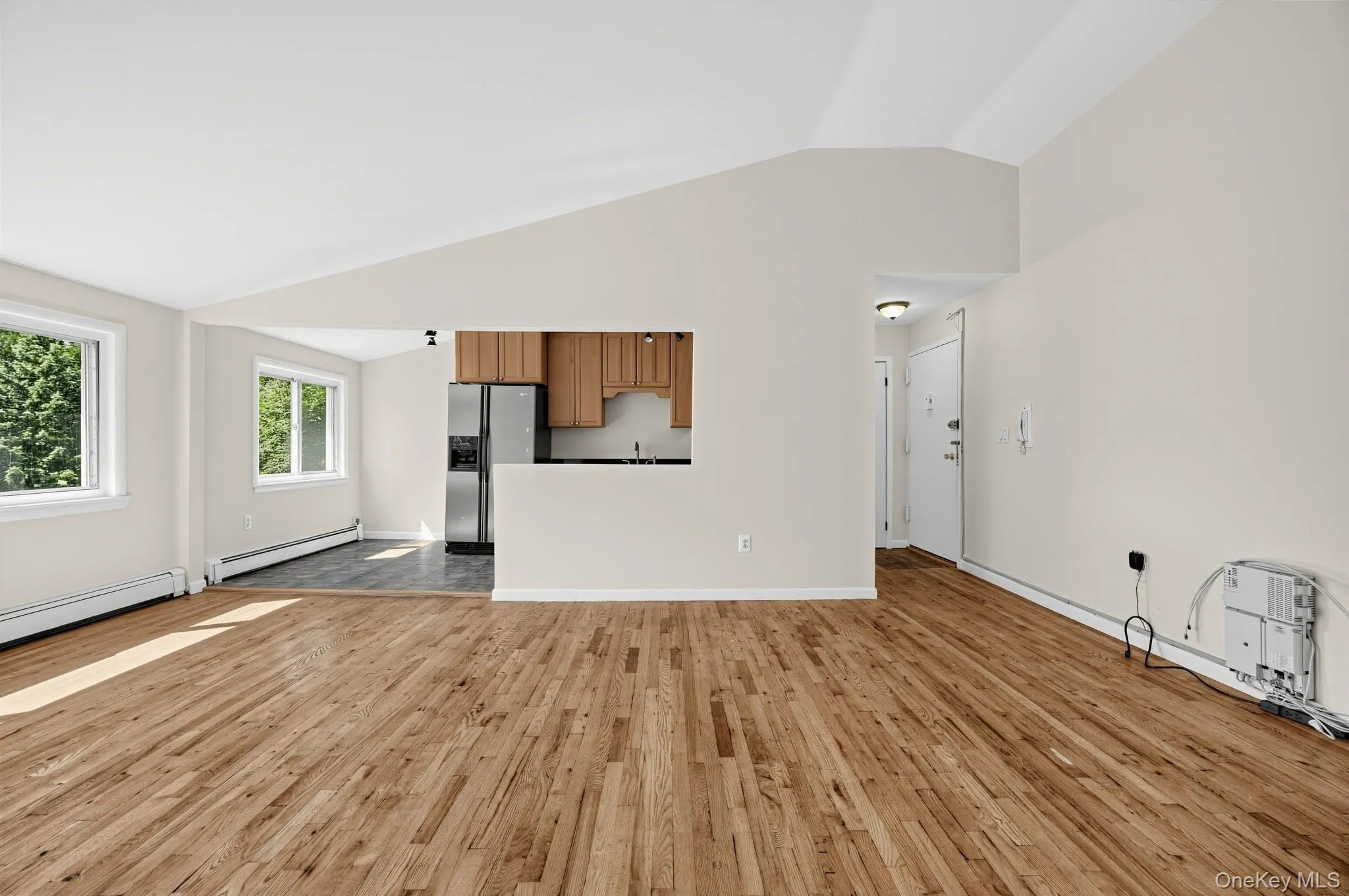 The living room as it actually appears — bright and spacious, with soaring ceiling height, abundant natural light and freshly cleaned and polished hardwood floors. The open sightline toward the kitchen/dining area adds to the sense of space. The living room as it actually appears — bright and spacious, with soaring ceiling height, abundant natural light and freshly cleaned and polished hardwood floors. The open sightline toward the kitchen/dining area adds to the sense of space.