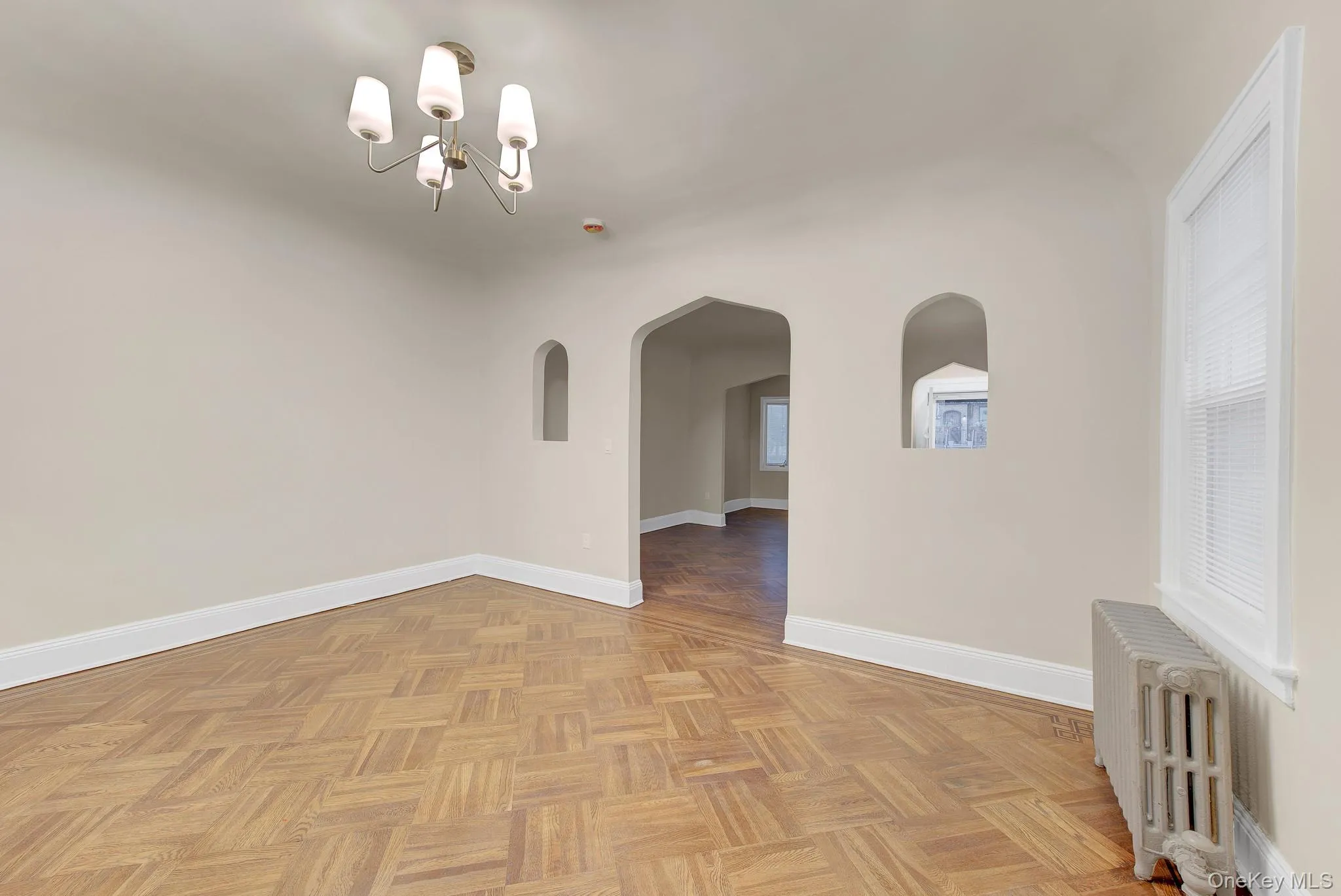 Parquet wood-finish flooring, arched doorway, recessed wall niches, contemporary chandelier, and window with blinds Parquet wood-finish flooring, arched doorway, recessed wall niches, contemporary chandelier, and window with blinds
