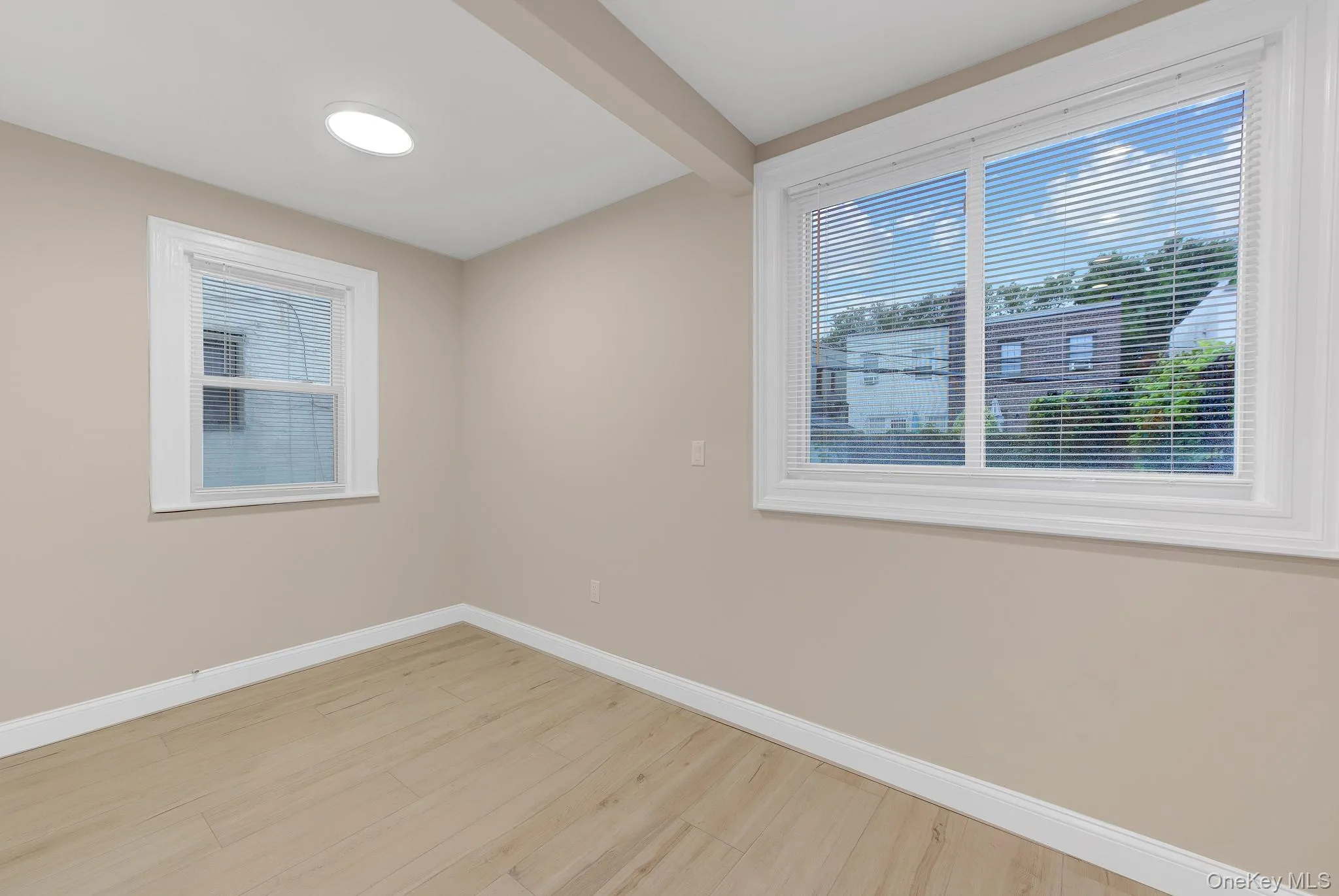 Neutral wall paint, wood-finish flooring, white window trim, and a ceiling light fixture Neutral wall paint, wood-finish flooring, white window trim, and a ceiling light fixture