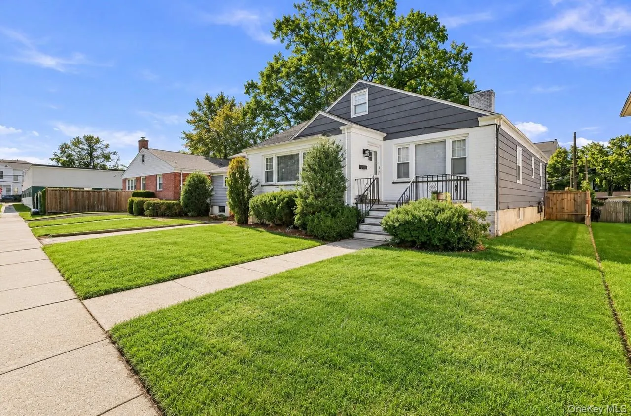 Single-family residence featuring a brick and siding exterior, front porch with metal railings, mature landscaping, and a concrete walkway Single-family residence featuring a brick and siding exterior, front porch with metal railings, mature landscaping, and a concrete walkway