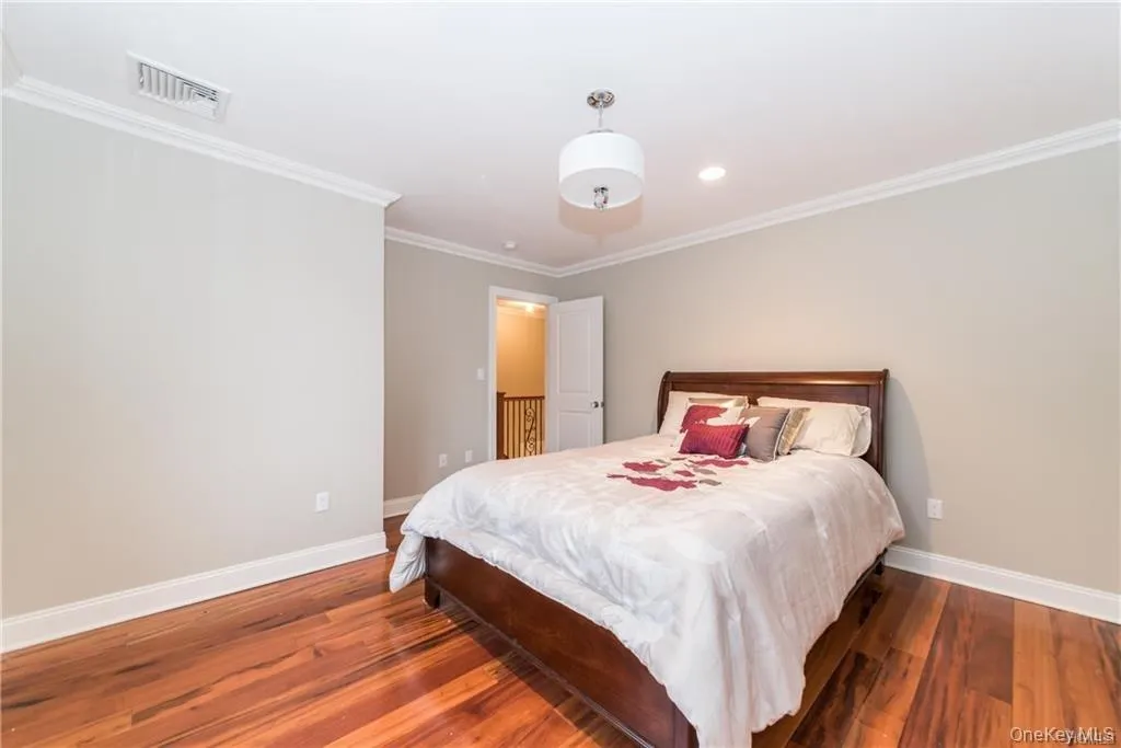 Bedroom featuring baseboards, wood finished floors, crown molding, and recessed lighting Bedroom featuring baseboards, wood finished floors, crown molding, and recessed lighting