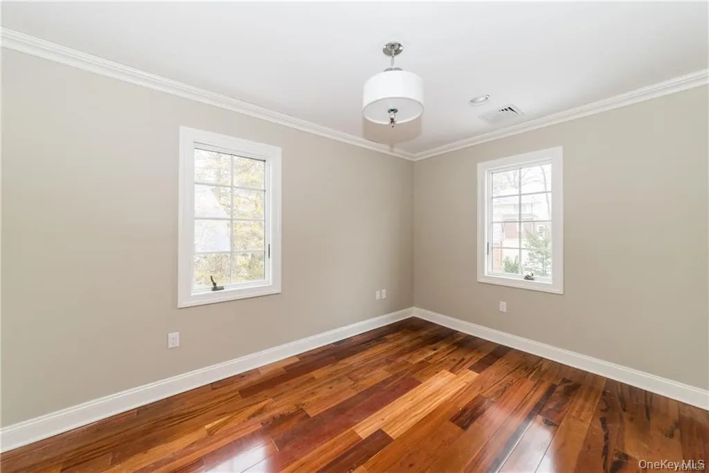 Unfurnished room with plenty of natural light, baseboards, hardwood / wood-style floors, and crown molding Unfurnished room with plenty of natural light, baseboards, hardwood / wood-style floors, and crown molding