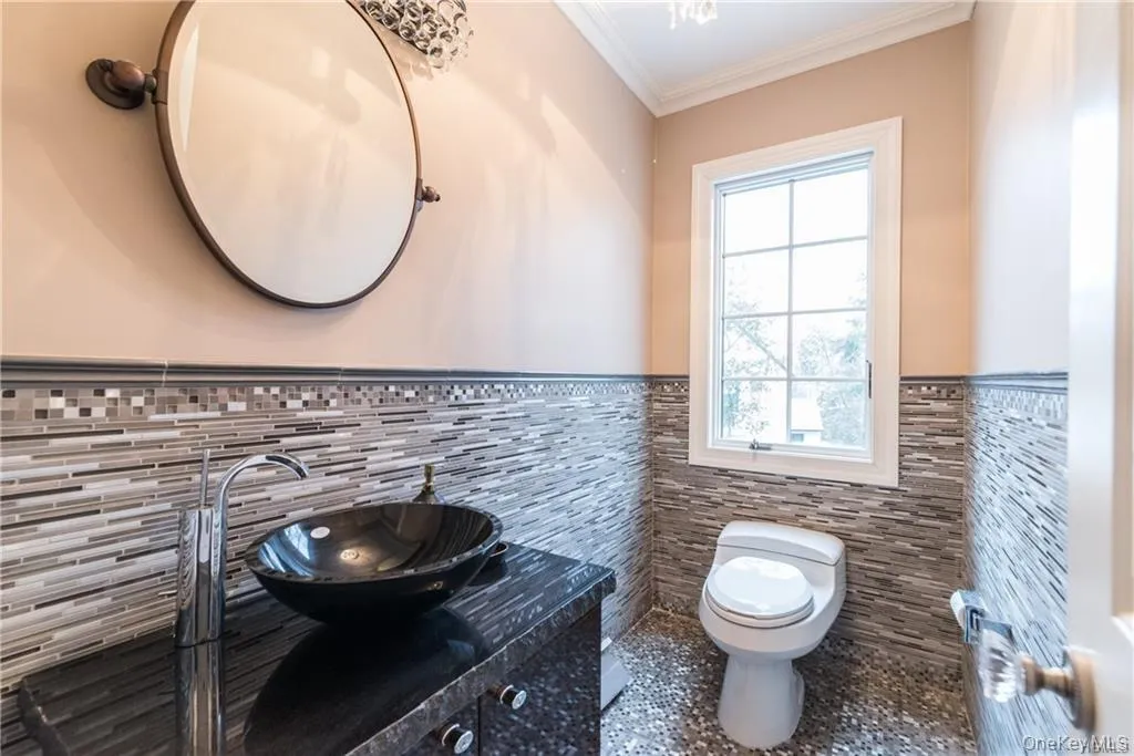 Bathroom with tile walls, wainscoting, toilet, tile patterned flooring, and vanity Bathroom with tile walls, wainscoting, toilet, tile patterned flooring, and vanity
