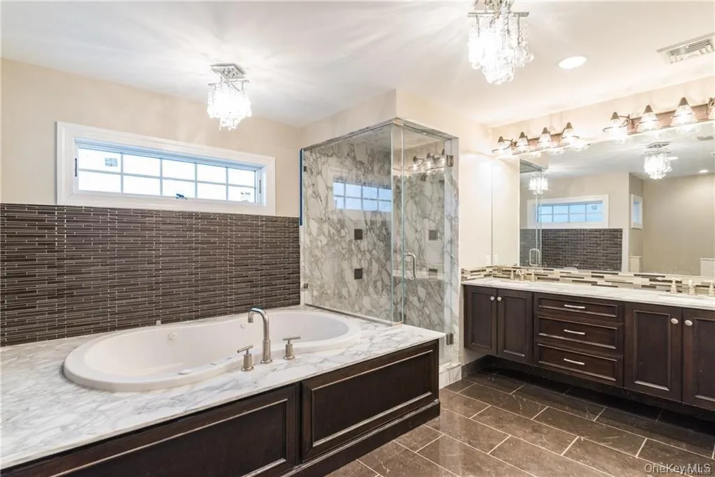 Bathroom with a chandelier, a stall shower, and a garden tub Bathroom with a chandelier, a stall shower, and a garden tub