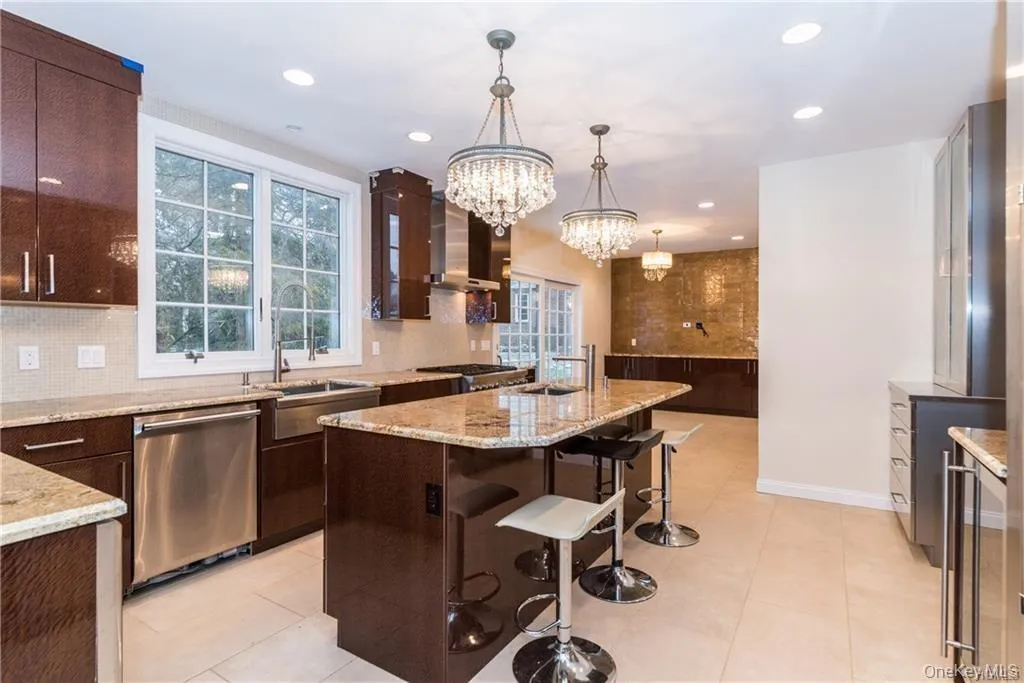 Kitchen with stainless steel appliances, wall chimney range hood, a sink, backsplash, and recessed lighting Kitchen with stainless steel appliances, wall chimney range hood, a sink, backsplash, and recessed lighting