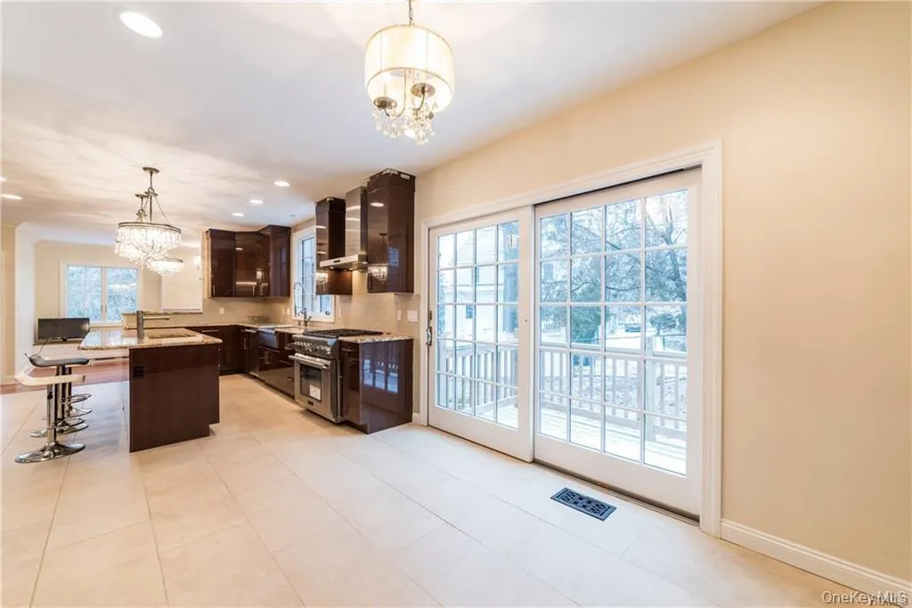 Kitchen with a chandelier, stainless steel stove, wall chimney exhaust hood, dark brown cabinets, and recessed lighting Kitchen with a chandelier, stainless steel stove, wall chimney exhaust hood, dark brown cabinets, and recessed lighting