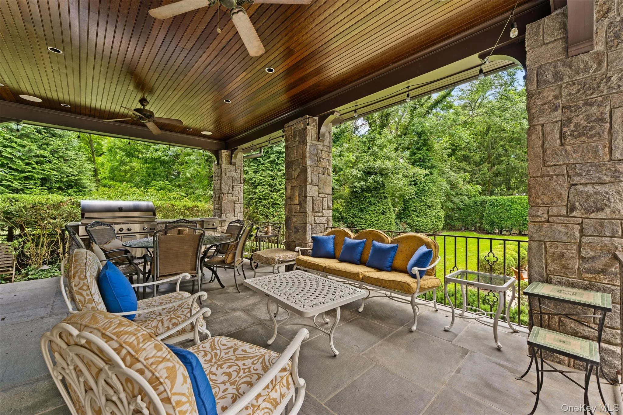 Covered patio with outdoor kitchen overlooking pool and grounds Covered patio with outdoor kitchen overlooking pool and grounds