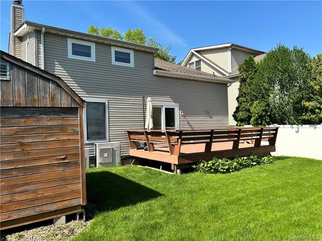 Rear view of property with a yard, a deck, and central air condition unit Rear view of property with a yard, a deck, and central air condition unit