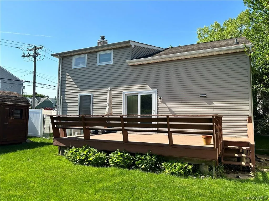 Rear view of property featuring a yard and a wooden deck Rear view of property featuring a yard and a wooden deck