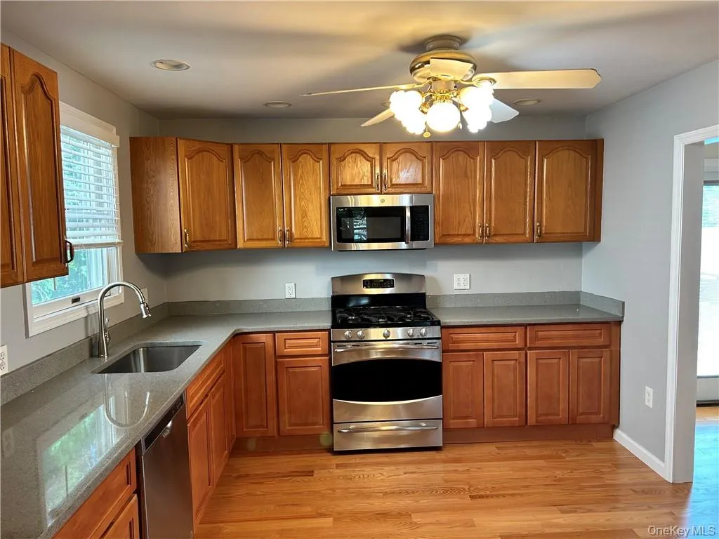 Kitchen featuring ceiling fan, stainless steel appliances, light hardwood / wood-style floors, and sink Kitchen featuring ceiling fan, stainless steel appliances, light hardwood / wood-style floors, and sink