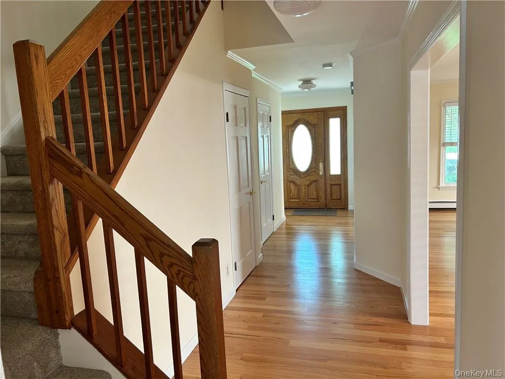 Foyer featuring a baseboard heating unit, crown molding, and light wood-type flooring Foyer featuring a baseboard heating unit, crown molding, and light wood-type flooring