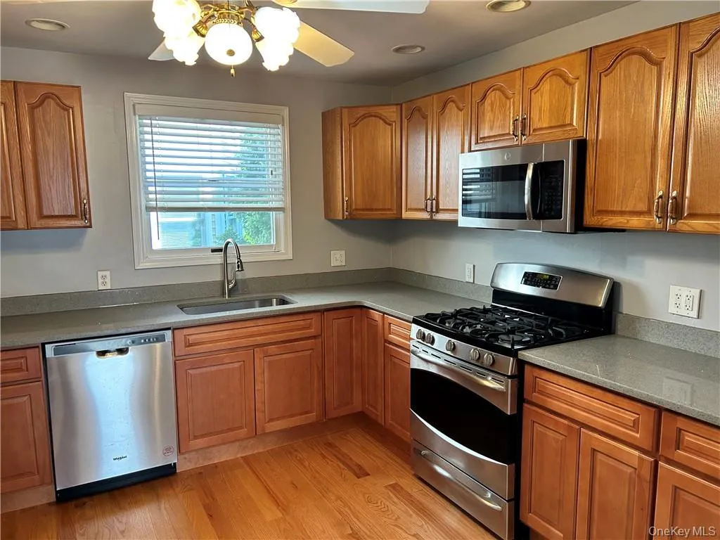 Kitchen featuring appliances with stainless steel finishes, sink, ceiling fan, and light hardwood / wood-style flooring Kitchen featuring appliances with stainless steel finishes, sink, ceiling fan, and light hardwood / wood-style flooring