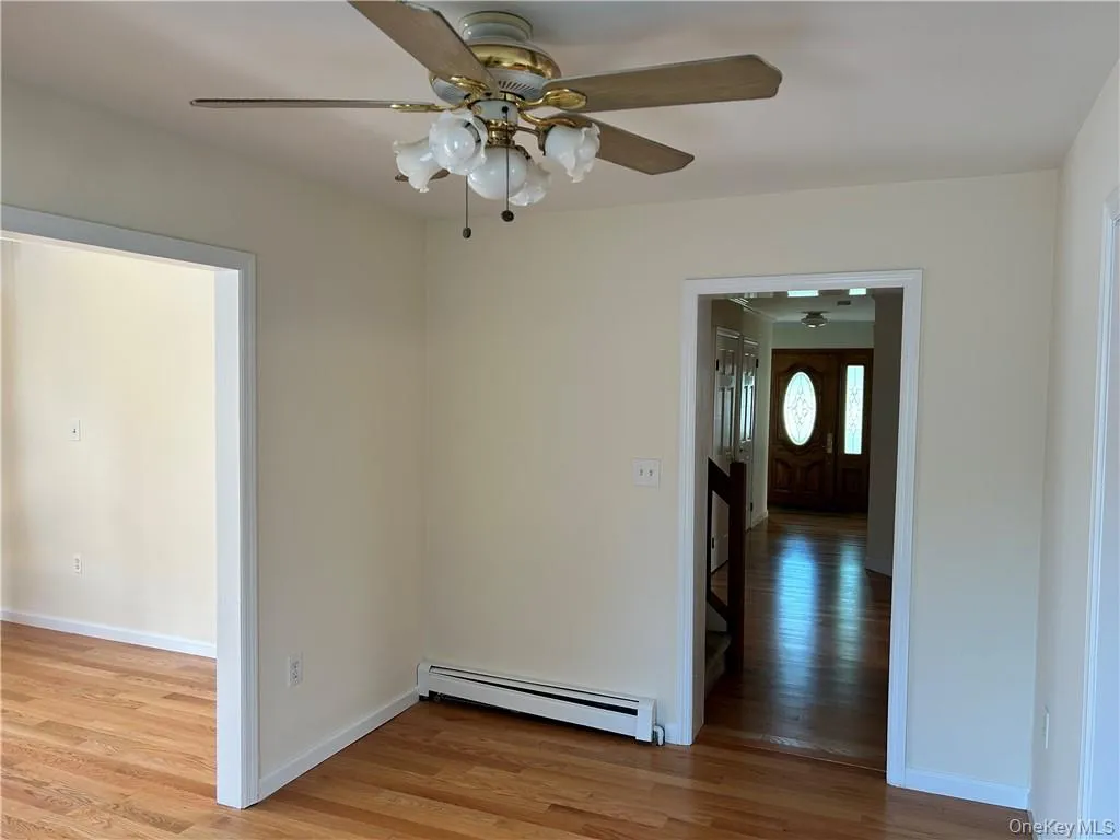 Spare room featuring hardwood / wood-style floors, ceiling fan, and a baseboard heating unit Spare room featuring hardwood / wood-style floors, ceiling fan, and a baseboard heating unit