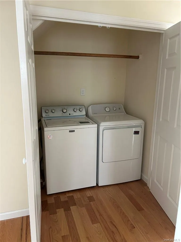 Clothes washing area with washing machine and dryer and hardwood / wood-style flooring Clothes washing area with washing machine and dryer and hardwood / wood-style flooring