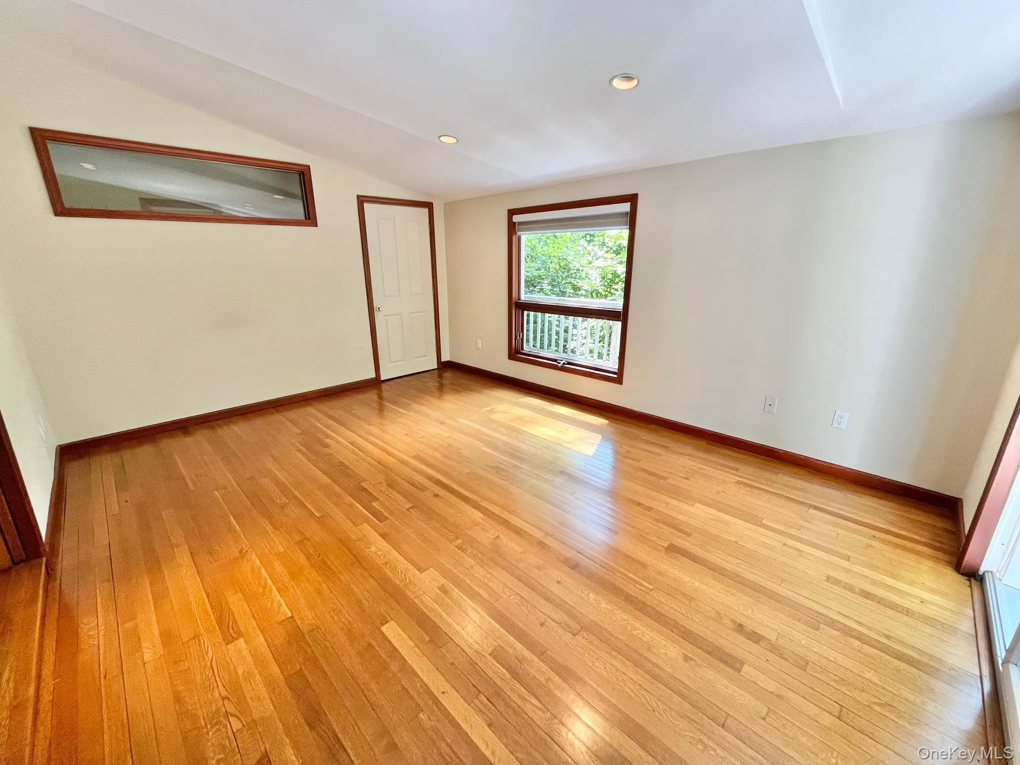 Empty room featuring light wood finished floors, vaulted ceiling, baseboards, and recessed lighting Empty room featuring light wood finished floors, vaulted ceiling, baseboards, and recessed lighting