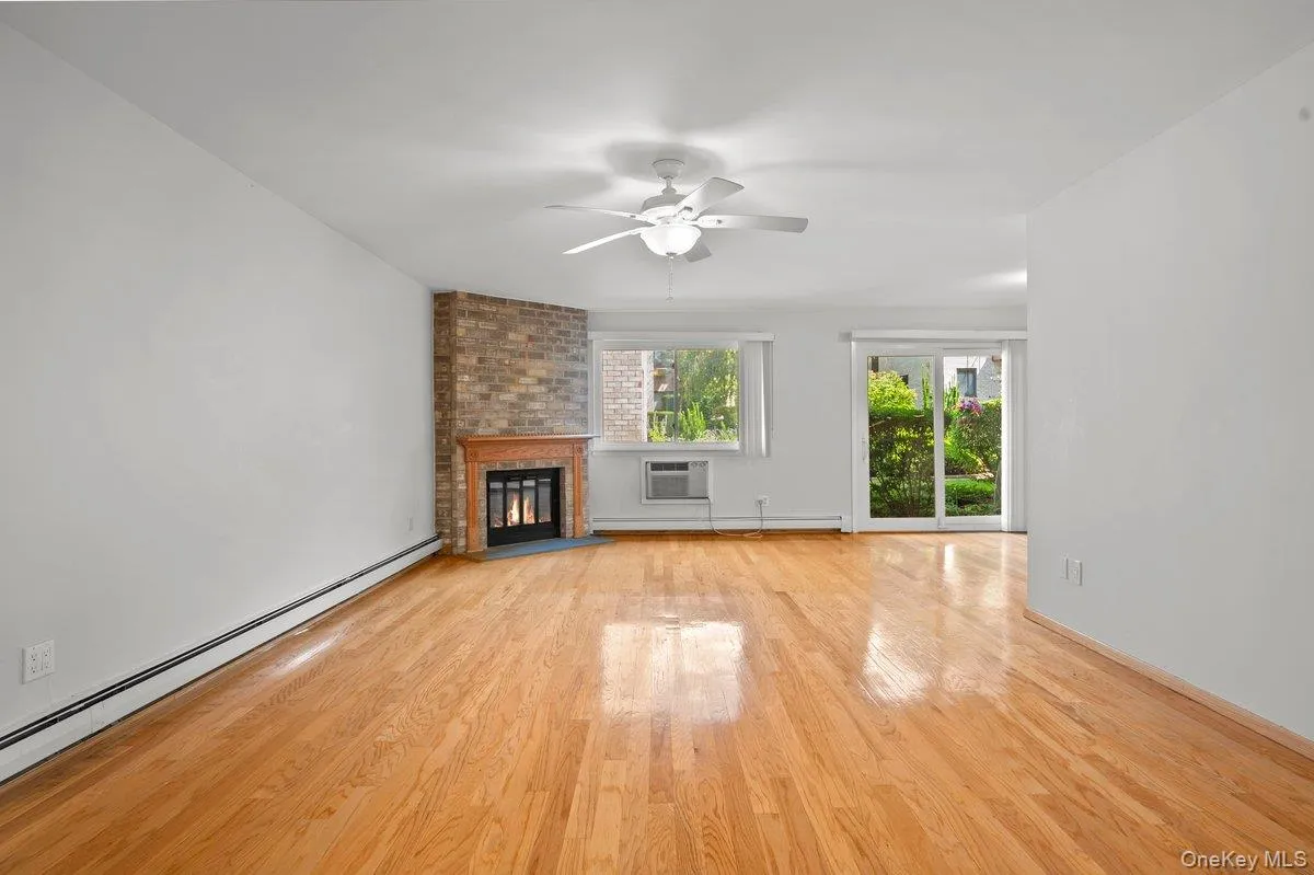 Hardwood flooring, brick fireplace with wood mantel, ceiling fan, large window, and sliding glass door Hardwood flooring, brick fireplace with wood mantel, ceiling fan, large window, and sliding glass door