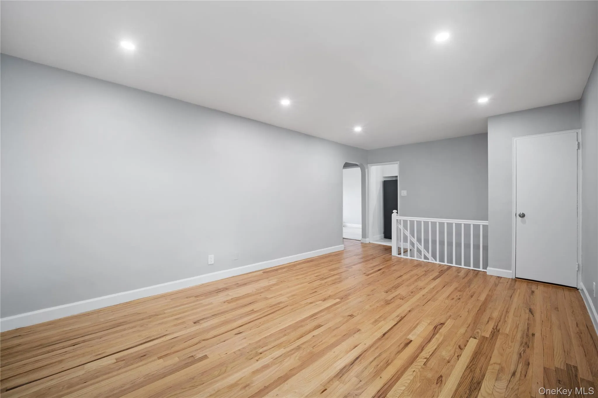 Hardwood flooring throughout, recessed lighting, neutral wall tones, white trim, and a white stair railing Hardwood flooring throughout, recessed lighting, neutral wall tones, white trim, and a white stair railing