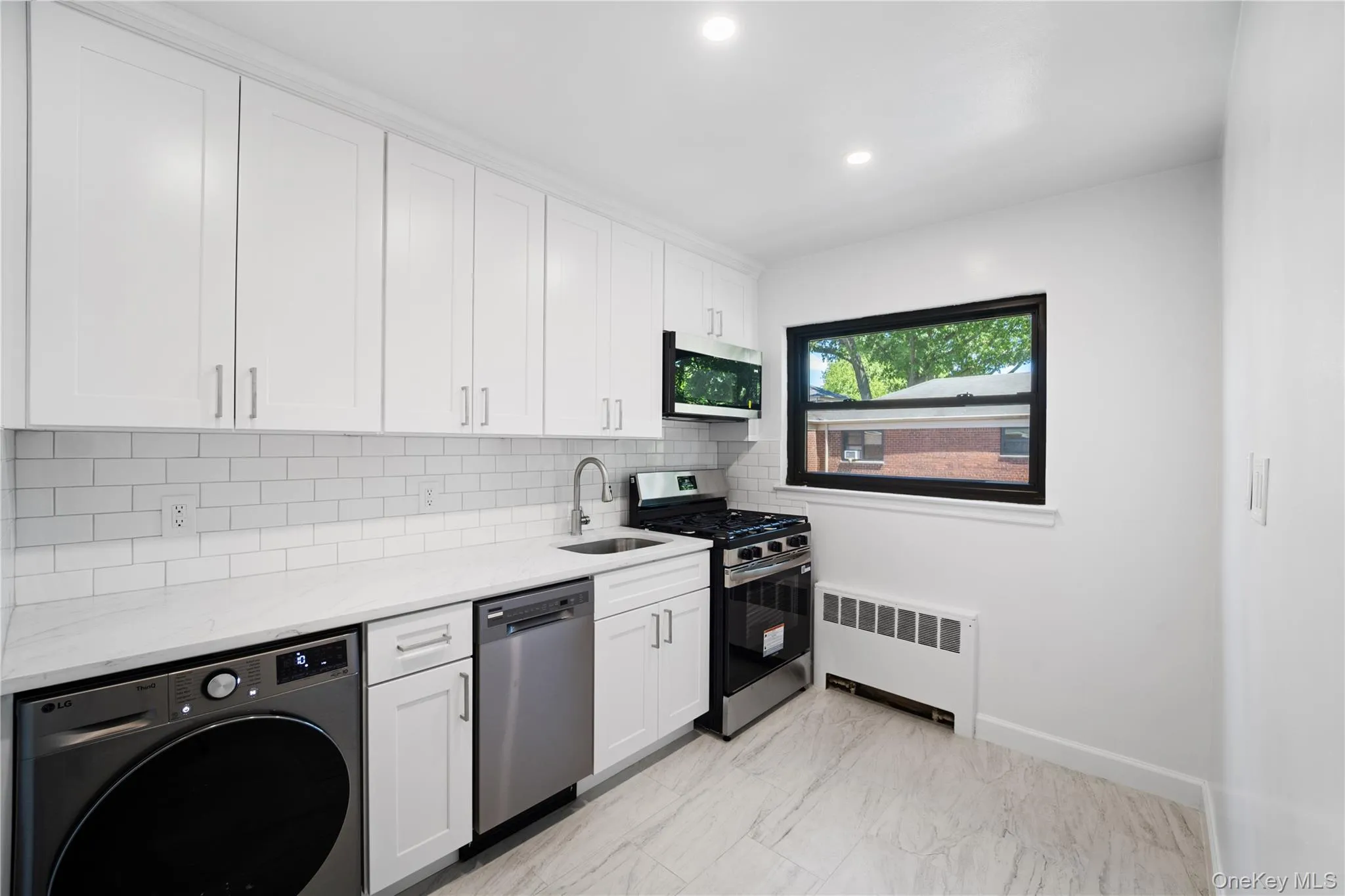 White shaker-style cabinetry, subway tile backsplash, stainless steel appliances, marble-finish flooring, and recessed lighting White shaker-style cabinetry, subway tile backsplash, stainless steel appliances, marble-finish flooring, and recessed lighting