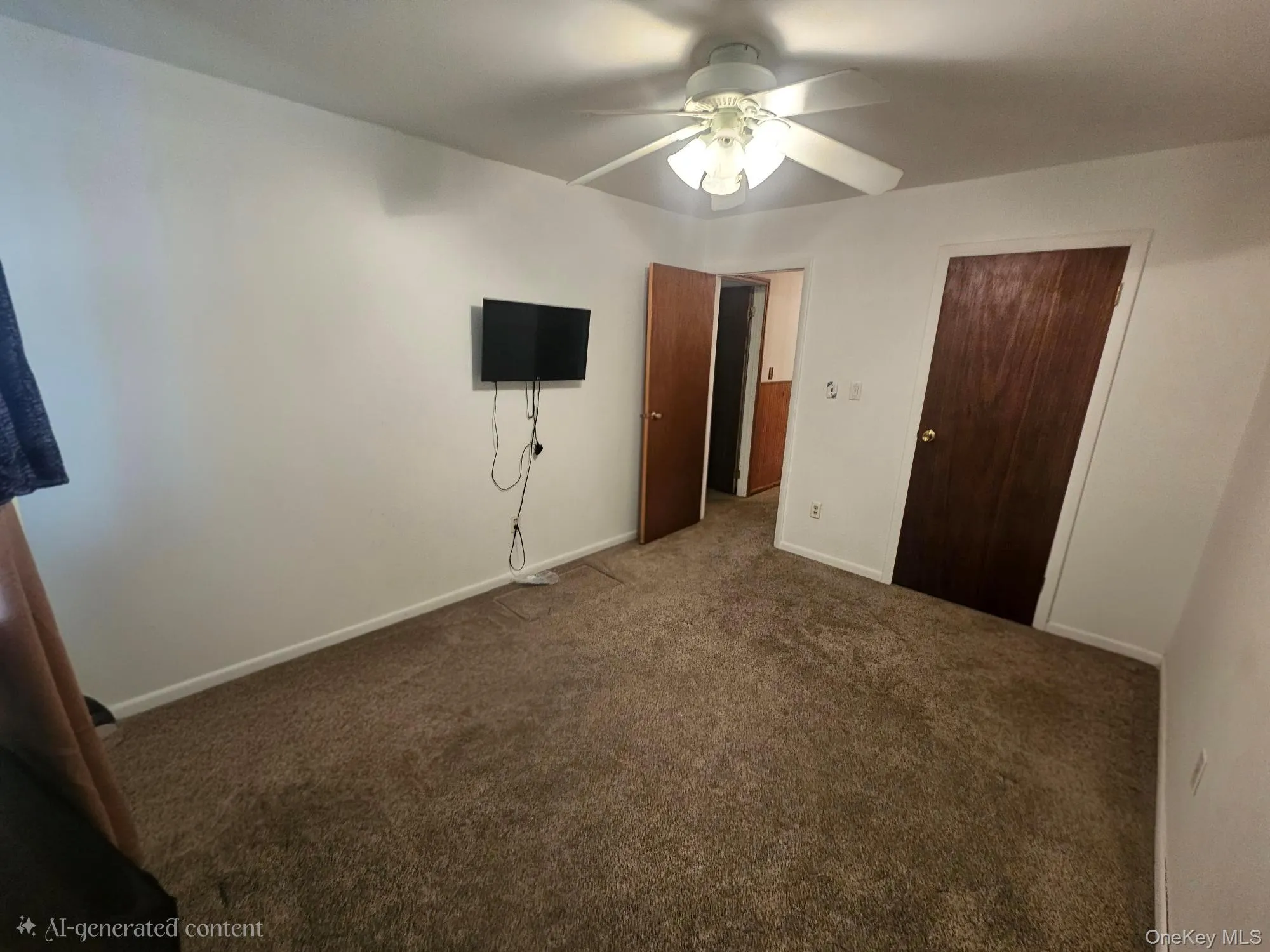 Wall-mounted television bracket, ceiling fan with integrated lighting, two wood-finish doors, and plush carpet flooring Wall-mounted television bracket, ceiling fan with integrated lighting, two wood-finish doors, and plush carpet flooring