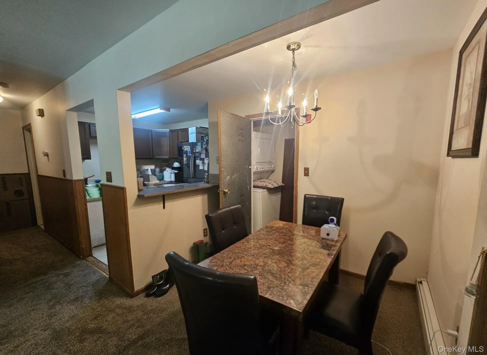 Dining area with chandelier, wood-finish wainscoting, and pass-through to kitchen Dining area with chandelier, wood-finish wainscoting, and pass-through to kitchen