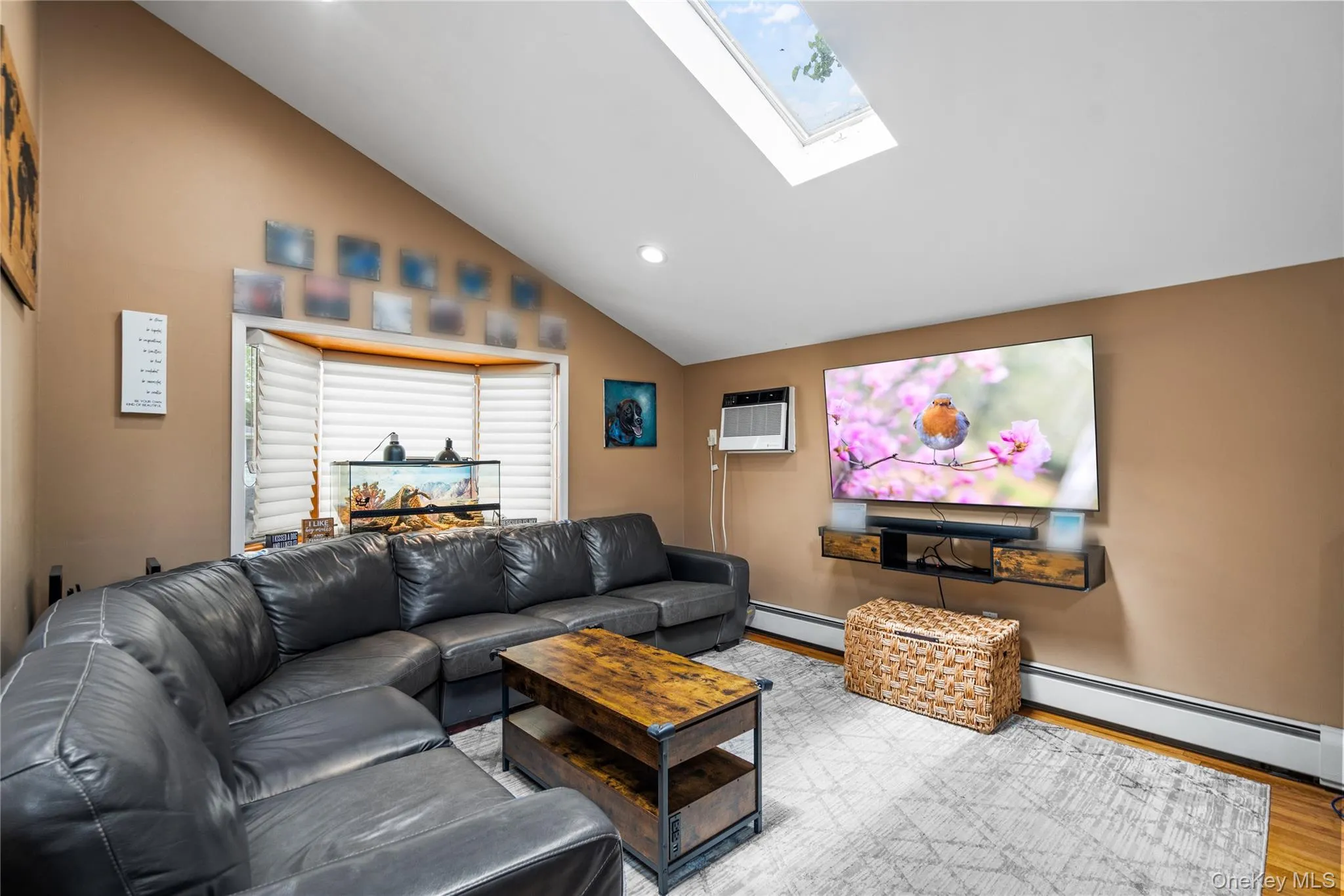 Living area with a skylight, baseboard heating, wood finished floors, lofted ceiling, and recessed lighting Living area with a skylight, baseboard heating, wood finished floors, lofted ceiling, and recessed lighting