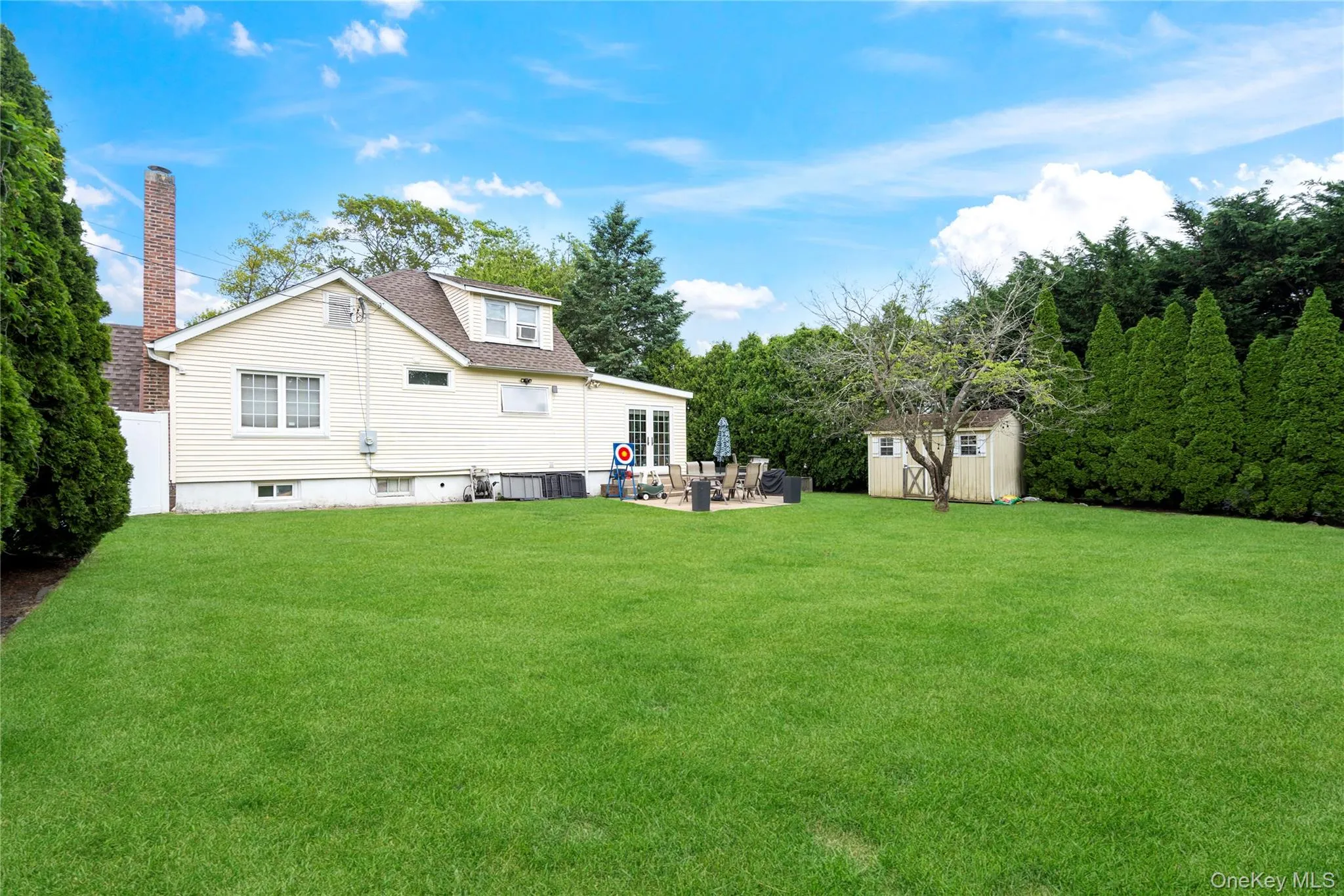 Rear view of house with a patio area, a lawn, central air condition unit, and roof with shingles Rear view of house with a patio area, a lawn, central air condition unit, and roof with shingles