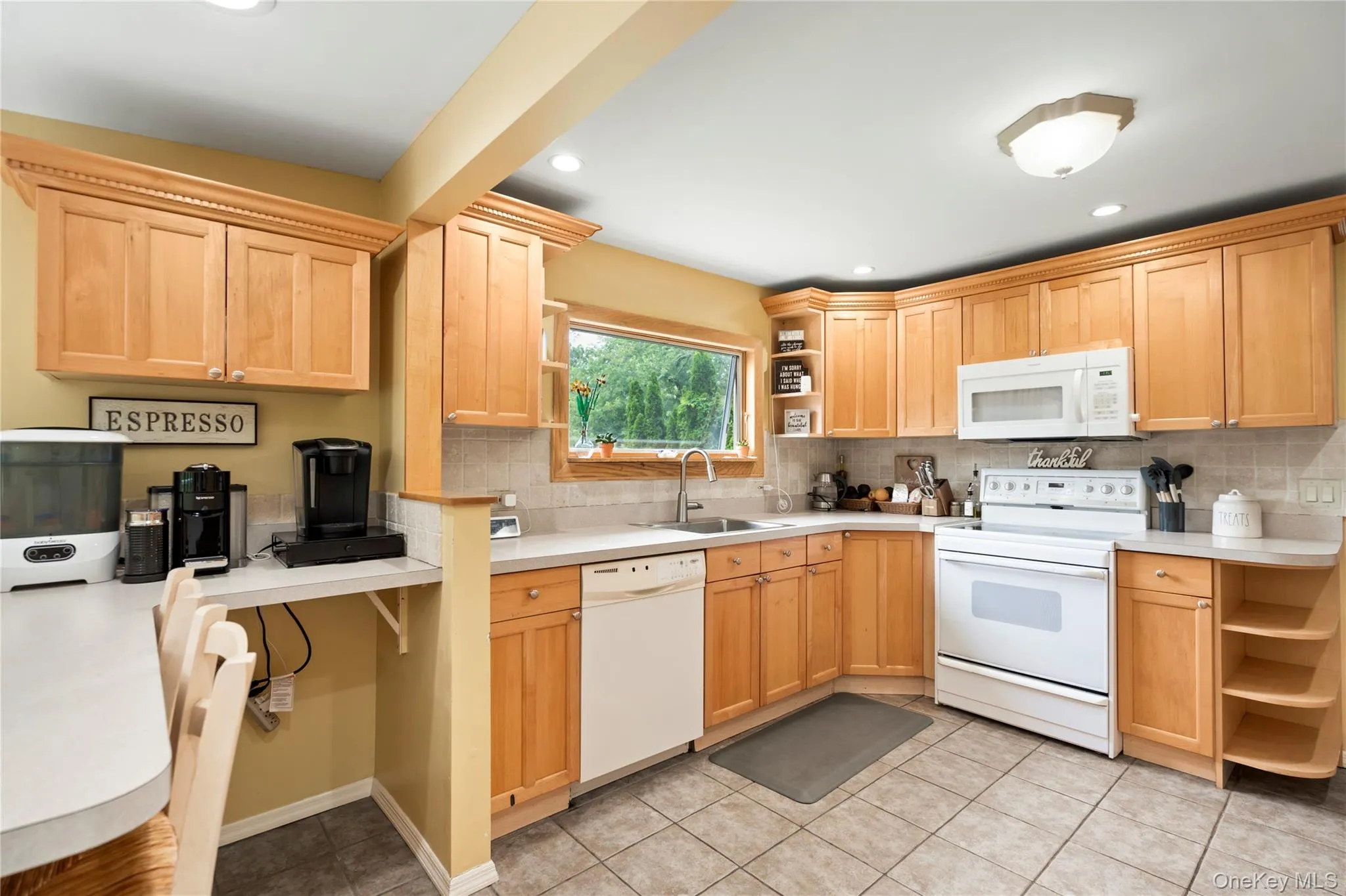 Kitchen featuring white appliances, open shelves, a sink, backsplash, and light countertops Kitchen featuring white appliances, open shelves, a sink, backsplash, and light countertops