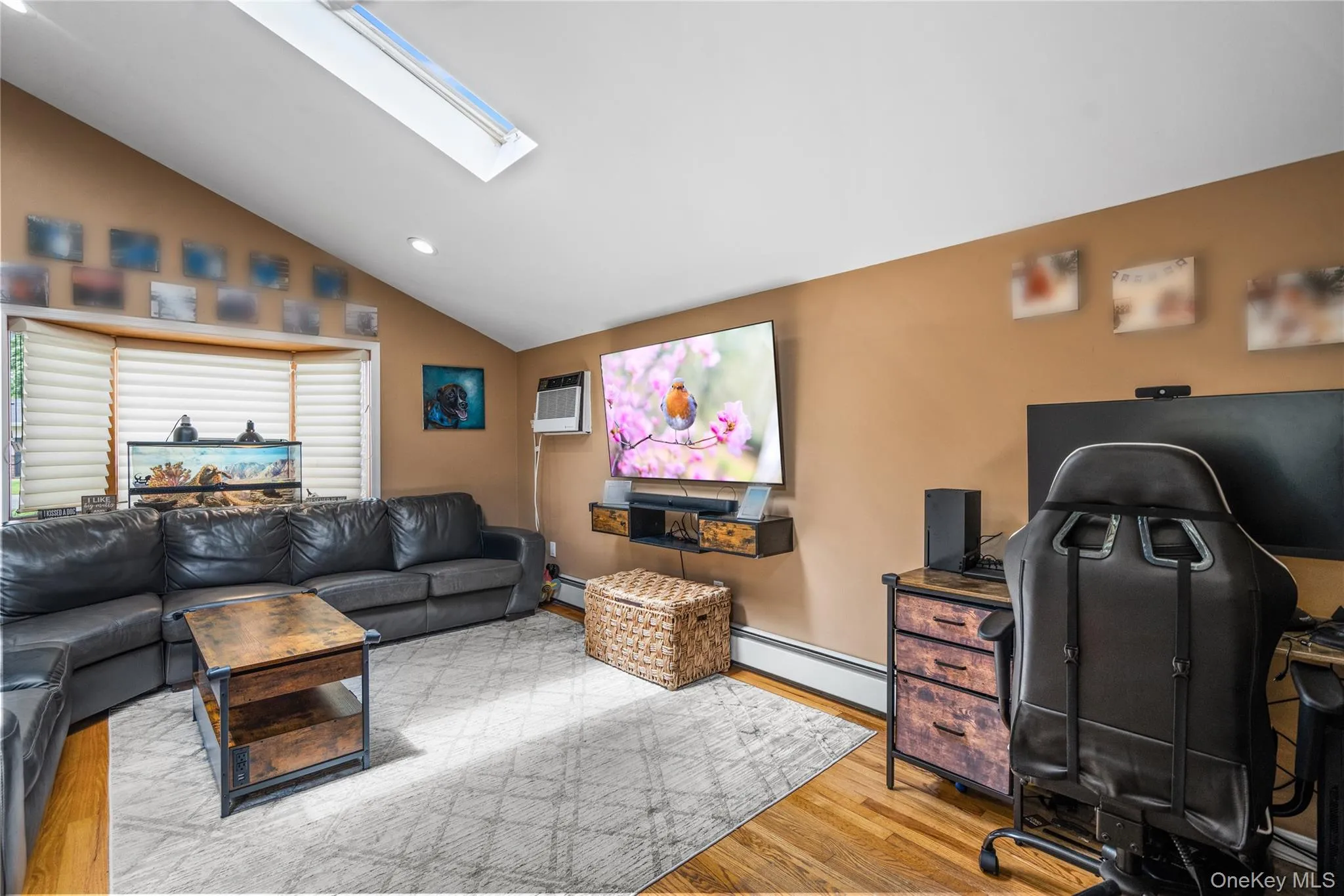 Living room featuring a baseboard radiator, a skylight, wood finished floors, vaulted ceiling, and recessed lighting Living room featuring a baseboard radiator, a skylight, wood finished floors, vaulted ceiling, and recessed lighting