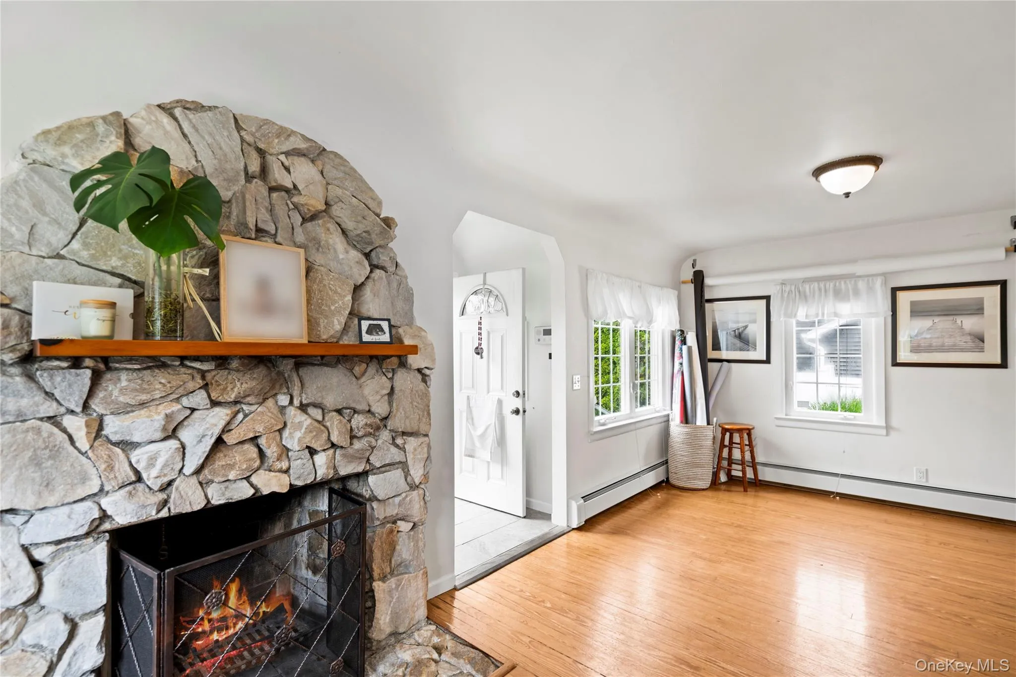 Unfurnished living room featuring wood finished floors, a baseboard heating unit, a fireplace, and baseboard heating Unfurnished living room featuring wood finished floors, a baseboard heating unit, a fireplace, and baseboard heating