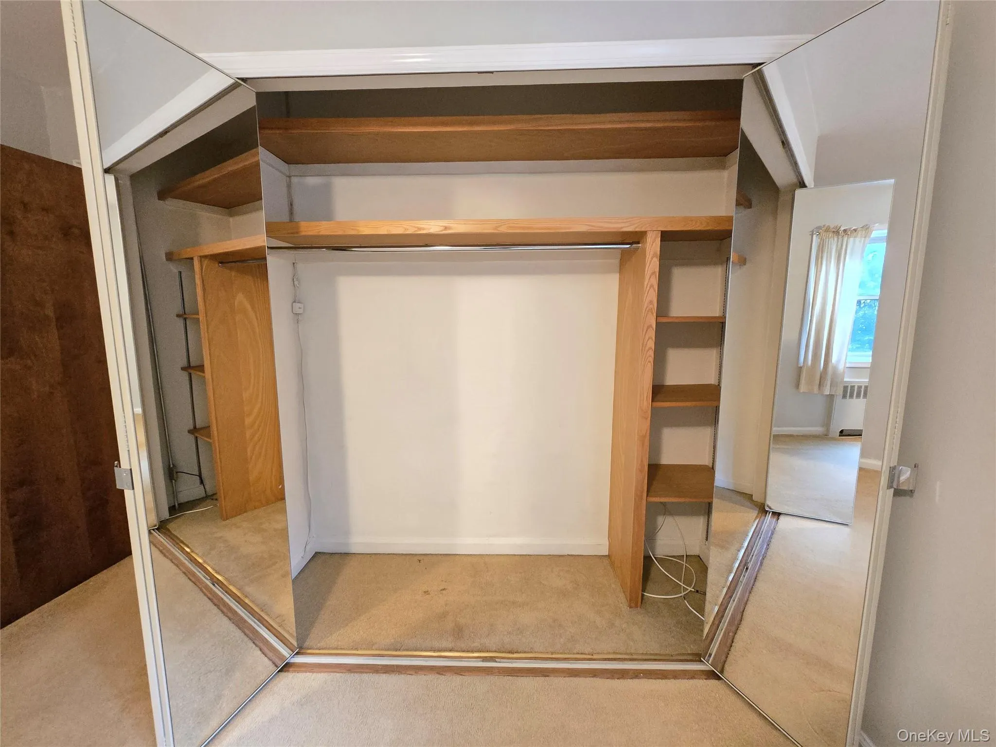 Bedroom closet with mirrored doors and built-in wood shelving. Bedroom closet with mirrored doors and built-in wood shelving.