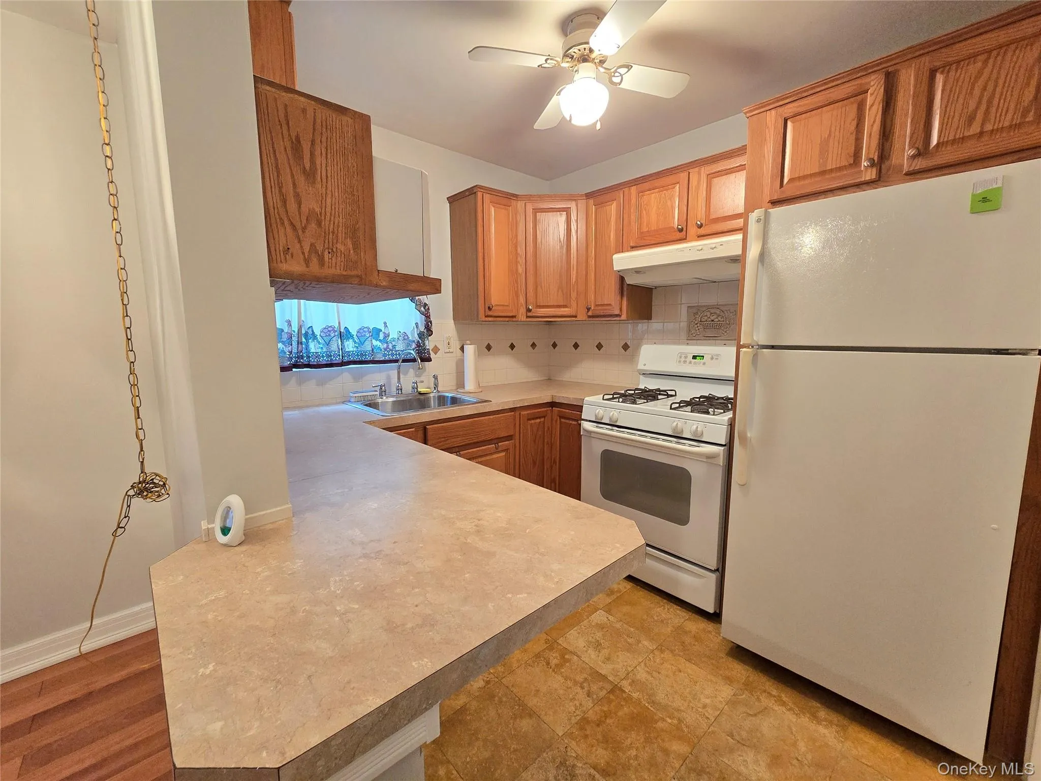 Windowed kitchen with gas range, full-size refrigerator, and oak cabinetry. Windowed kitchen with gas range, full-size refrigerator, and oak cabinetry.