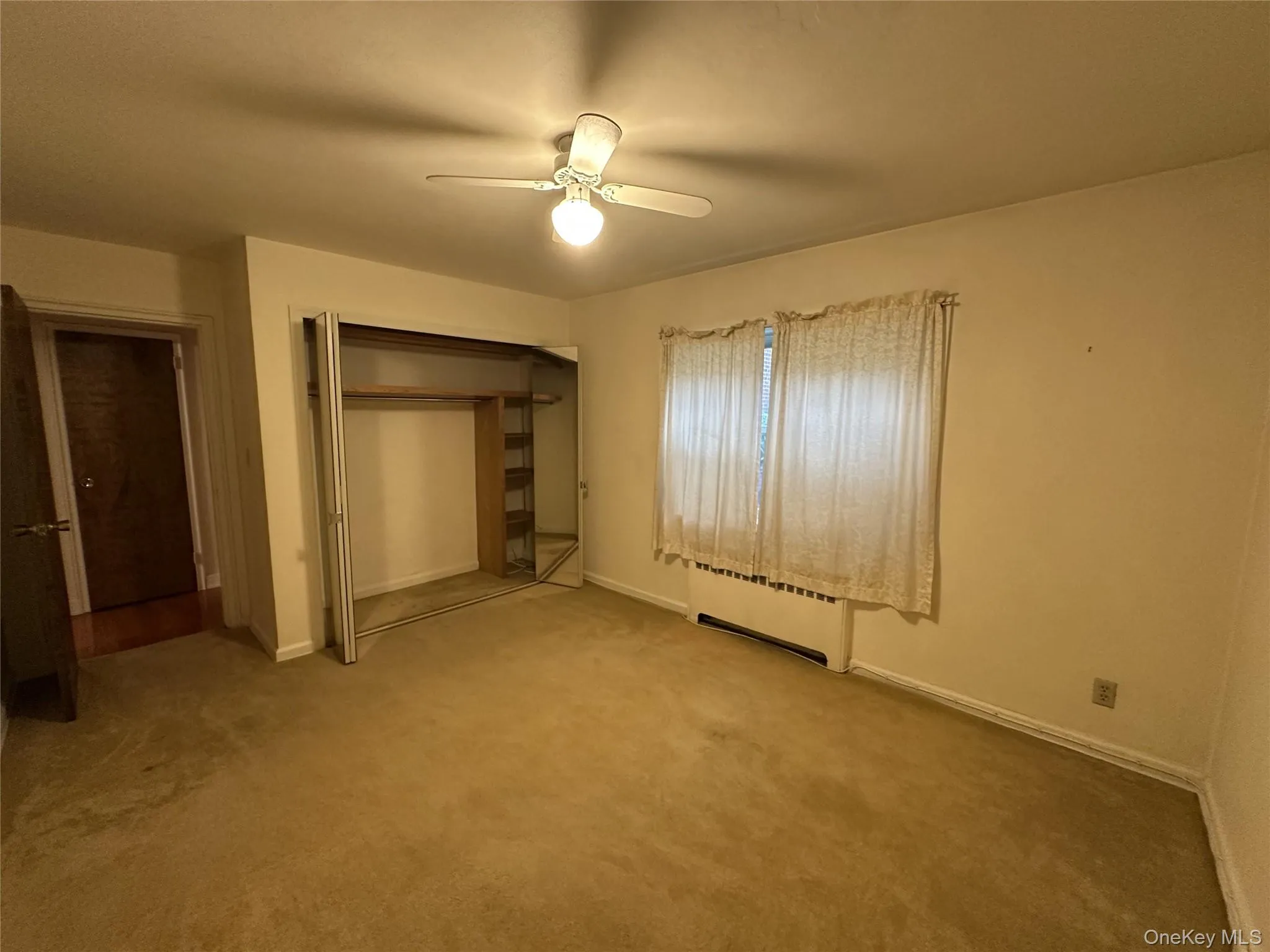Bedroom with a mirrored double closet, ceiling fan, and window. Bedroom with a mirrored double closet, ceiling fan, and window.