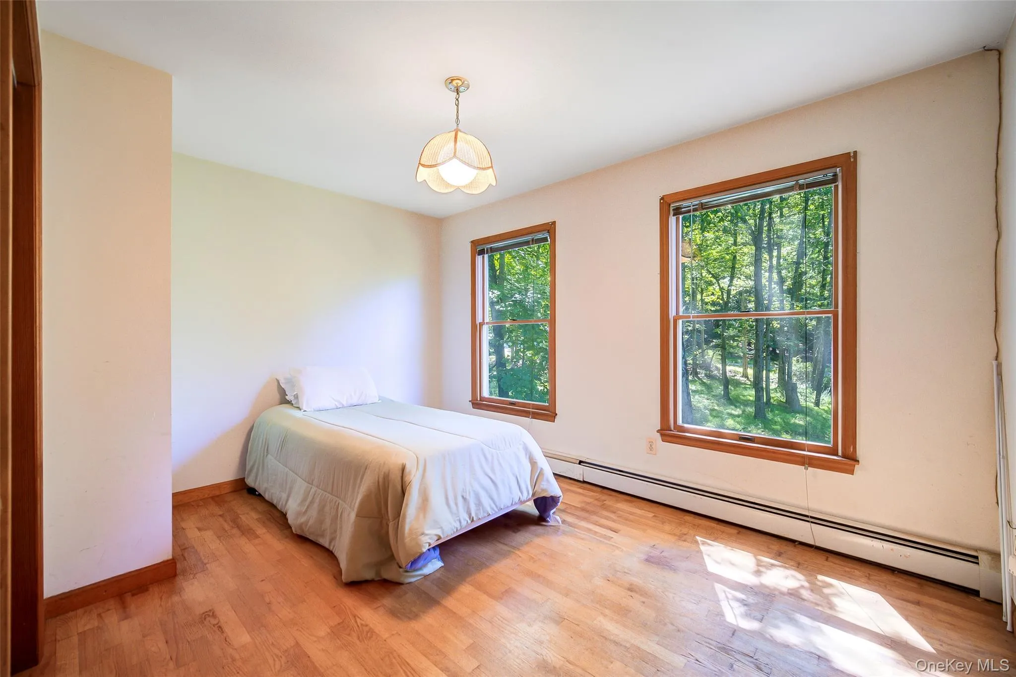 Hardwood flooring, two large windows, wood window trim, a ceiling-mounted light fixture, and light-toned wall finishes Hardwood flooring, two large windows, wood window trim, a ceiling-mounted light fixture, and light-toned wall finishes