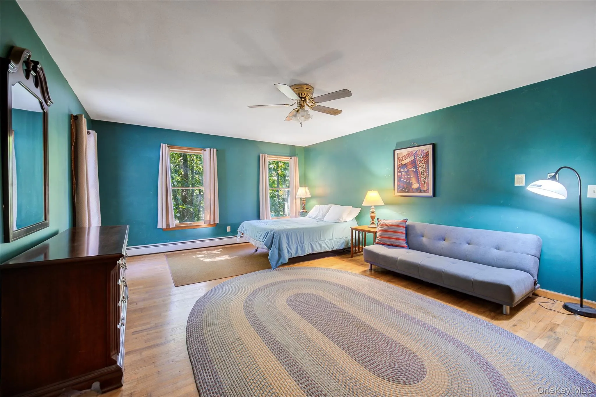 Spacious room with hardwood flooring, multiple windows, and a ceiling fan Spacious room with hardwood flooring, multiple windows, and a ceiling fan