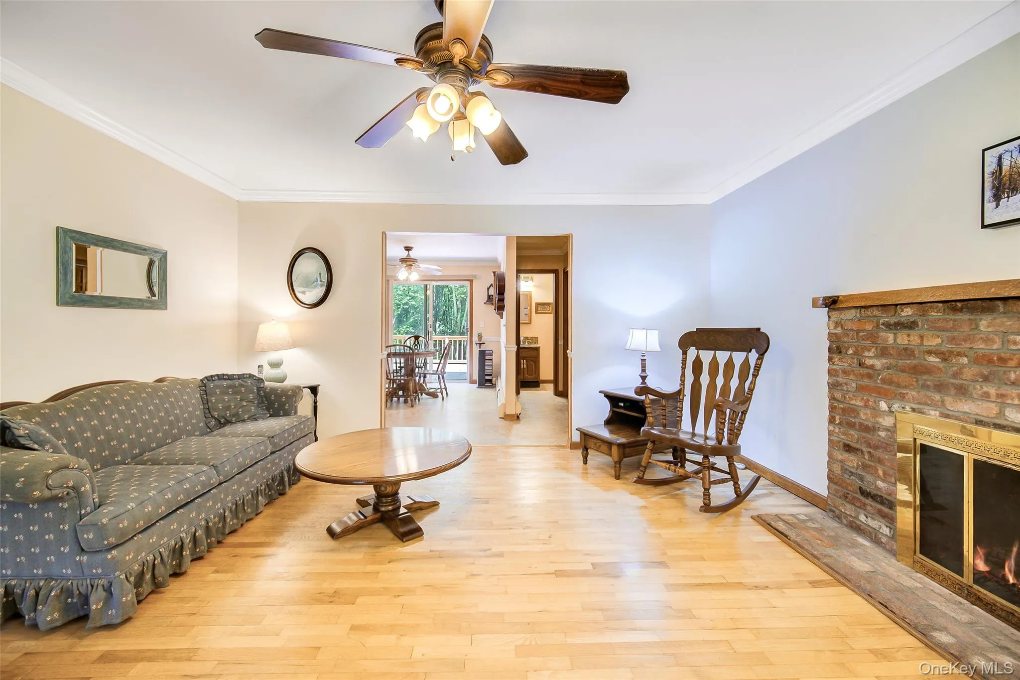 Wood fireplace has a brass-trimmed firebox, crown molding, and a ceiling fan make this room cozy on warm winter nights Wood fireplace has a brass-trimmed firebox, crown molding, and a ceiling fan make this room cozy on warm winter nights