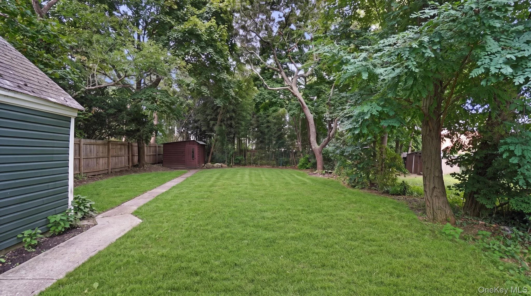 Expansive lawn with mature trees and a privacy fence Expansive lawn with mature trees and a privacy fence