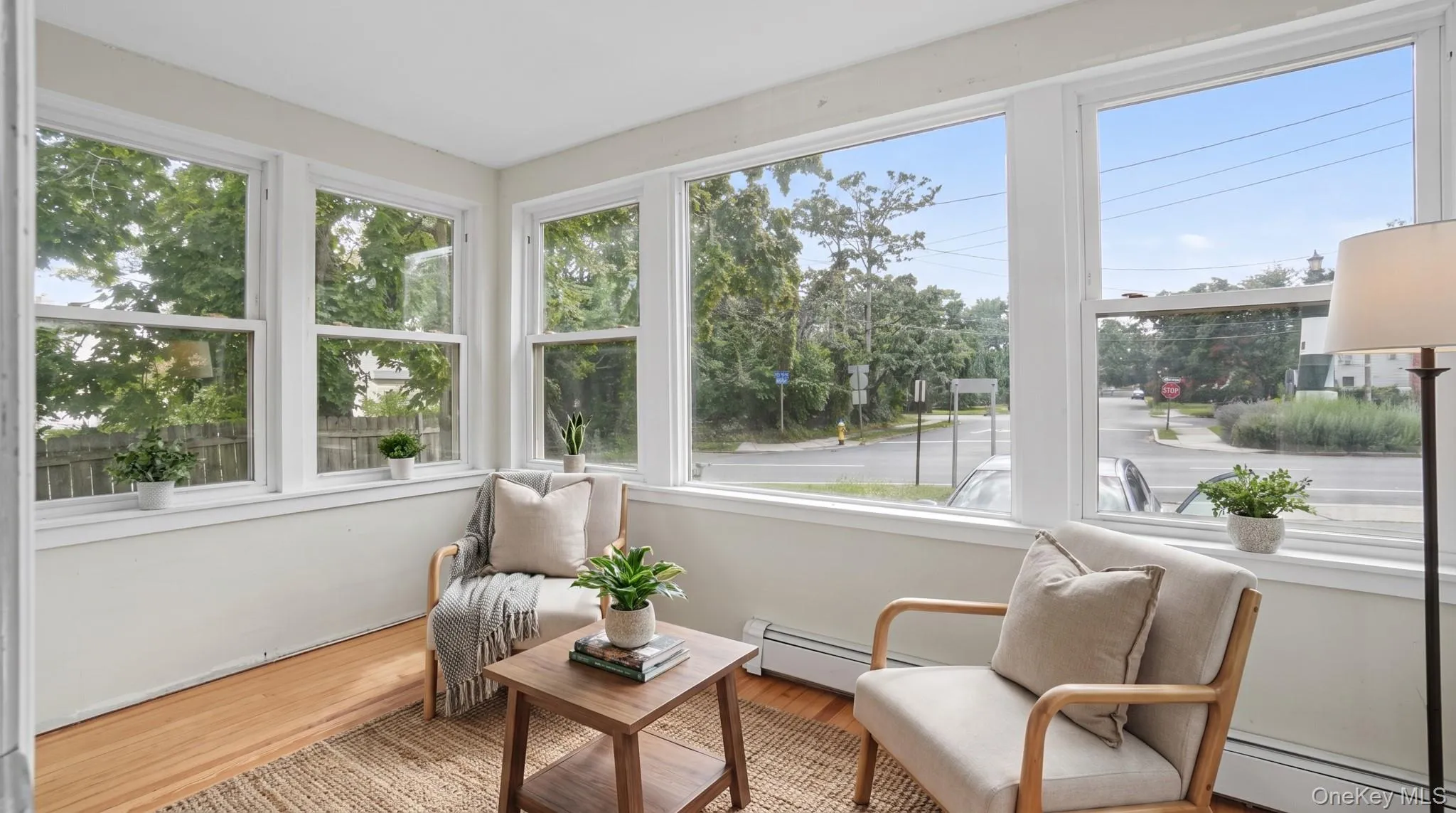 Sun-filled room featuring multiple large windows, wood-finish flooring, and white trim Sun-filled room featuring multiple large windows, wood-finish flooring, and white trim