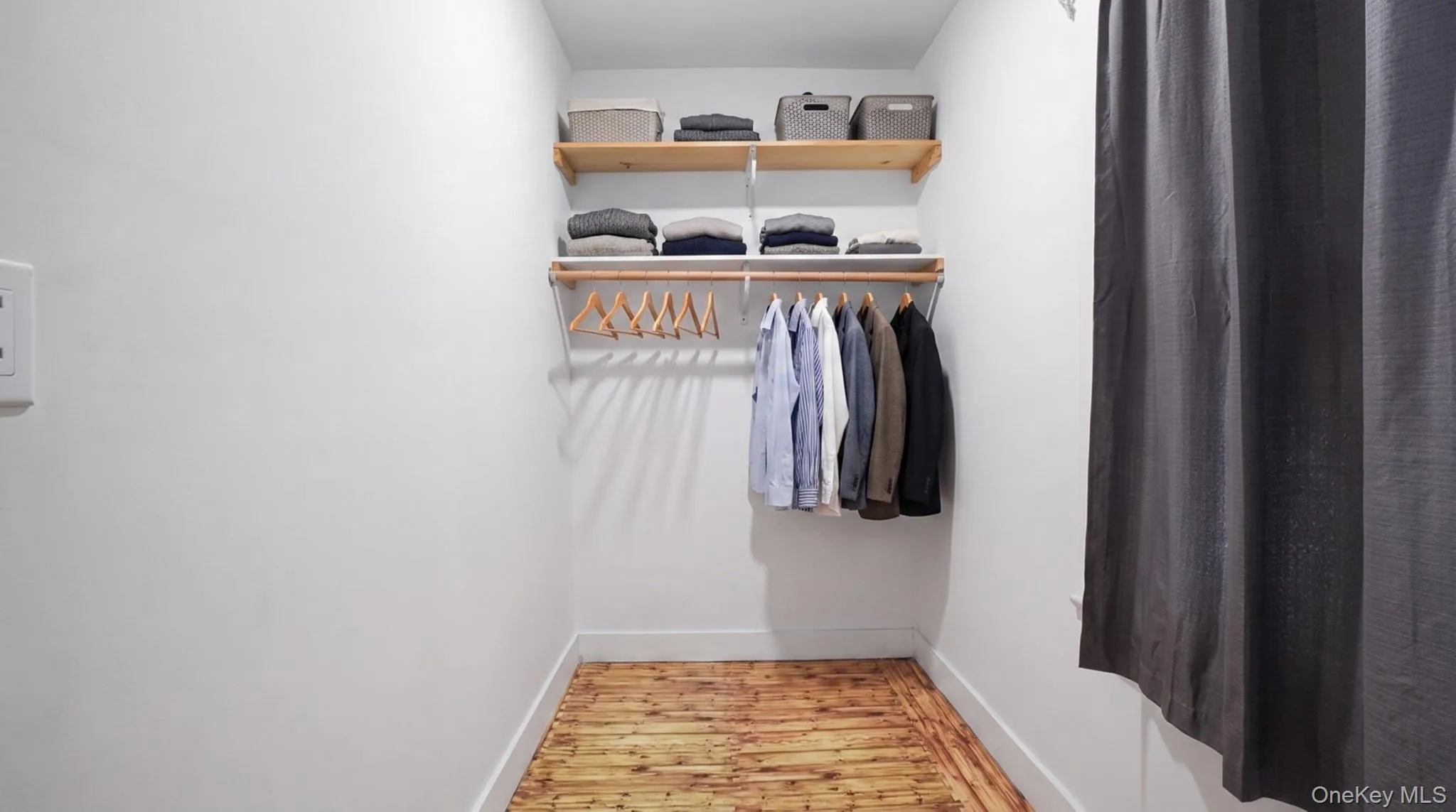 Warm wood-finish flooring, built-in shelving, and a hanging rod Warm wood-finish flooring, built-in shelving, and a hanging rod