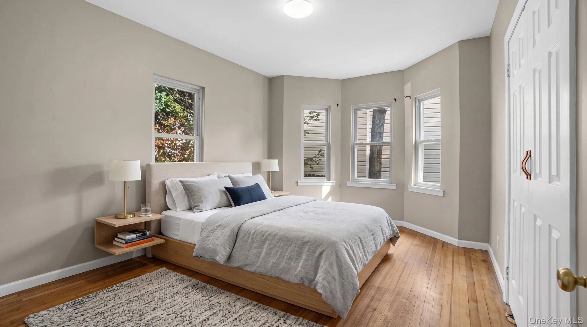 Hardwood flooring throughout, multiple windows, and a ceiling-mounted light fixture Hardwood flooring throughout, multiple windows, and a ceiling-mounted light fixture