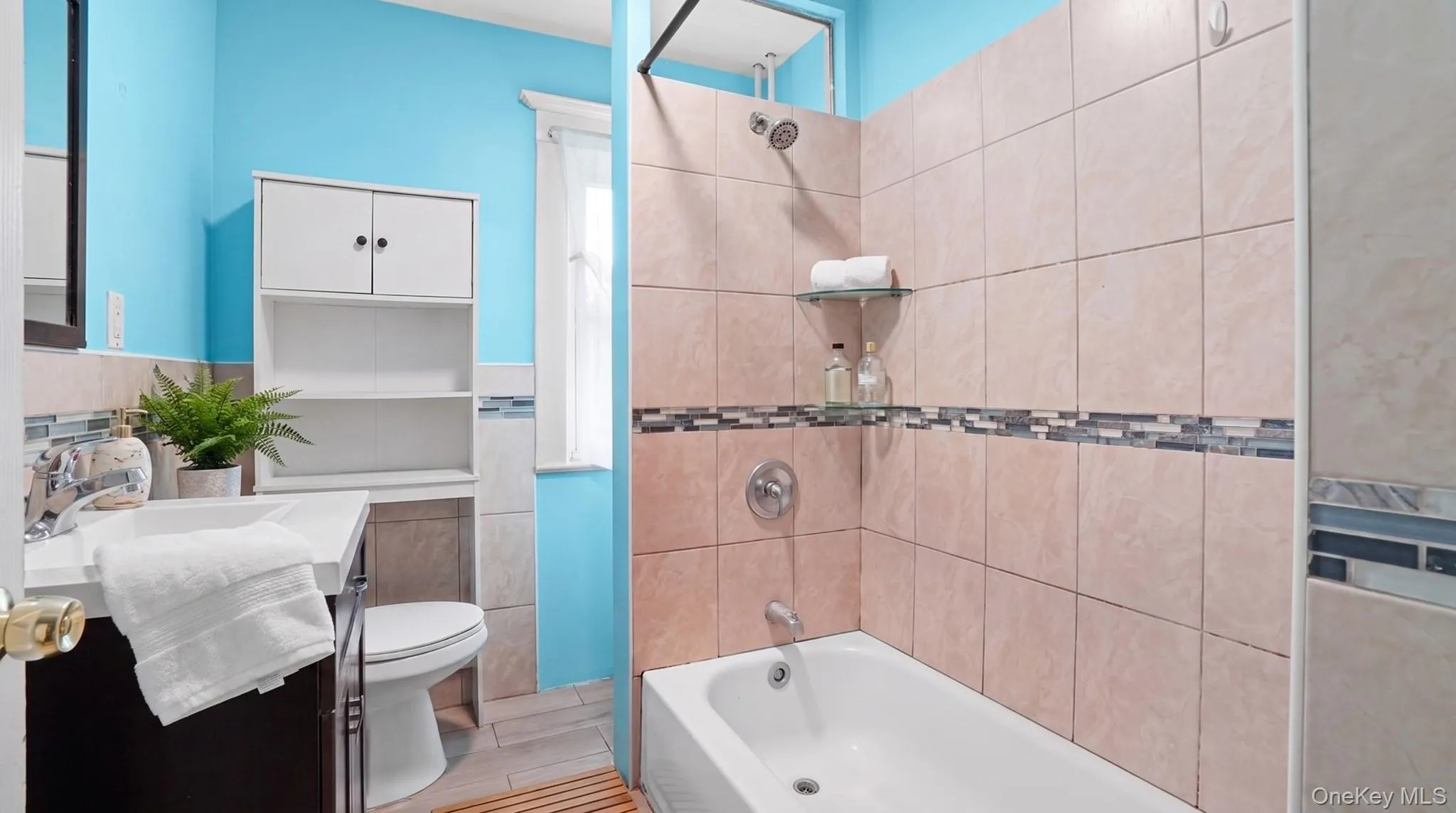 Bathtub with ceramic tile surround, mosaic accent band, and built-in glass shelving Bathtub with ceramic tile surround, mosaic accent band, and built-in glass shelving