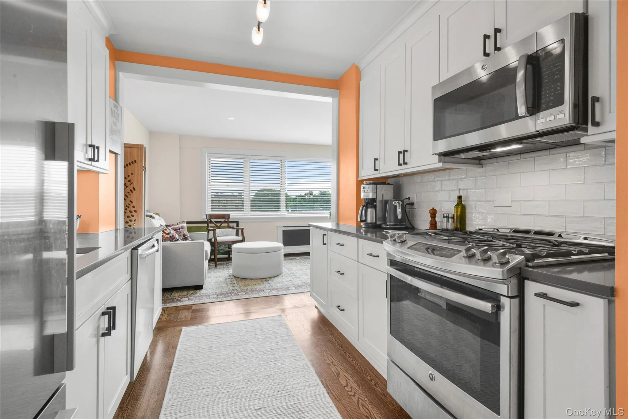 Galley kitchen featuring white cabinetry, dark countertops, and stainless steel appliances Galley kitchen featuring white cabinetry, dark countertops, and stainless steel appliances