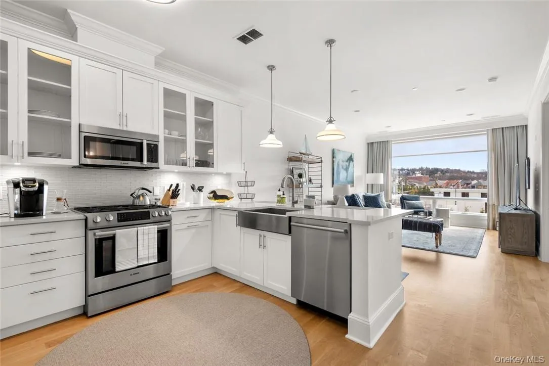 Kitchen with pendant lighting, sink, white cabinetry, and stainless steel appliances Kitchen with pendant lighting, sink, white cabinetry, and stainless steel appliances