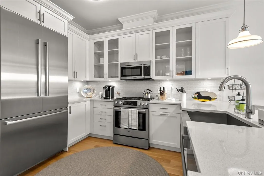 Kitchen featuring light stone countertops, sink, white cabinetry, stainless steel appliances, and light hardwood / wood-style flooring Kitchen featuring light stone countertops, sink, white cabinetry, stainless steel appliances, and light hardwood / wood-style flooring