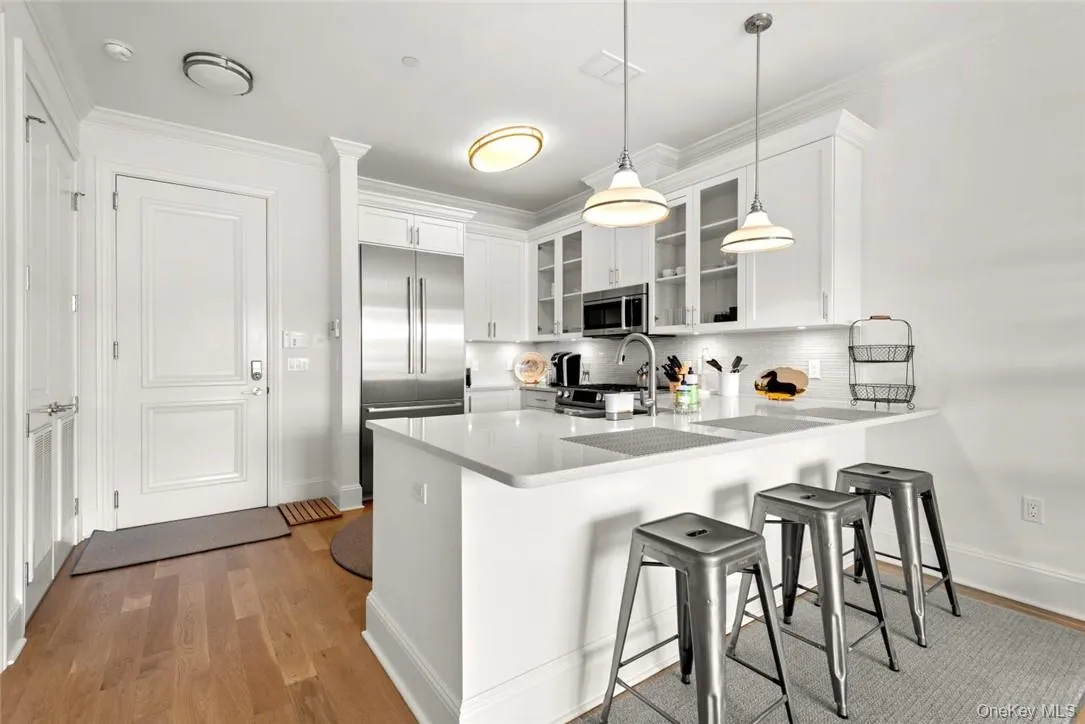Kitchen featuring appliances with stainless steel finishes, kitchen peninsula, pendant lighting, and white cabinetry Kitchen featuring appliances with stainless steel finishes, kitchen peninsula, pendant lighting, and white cabinetry