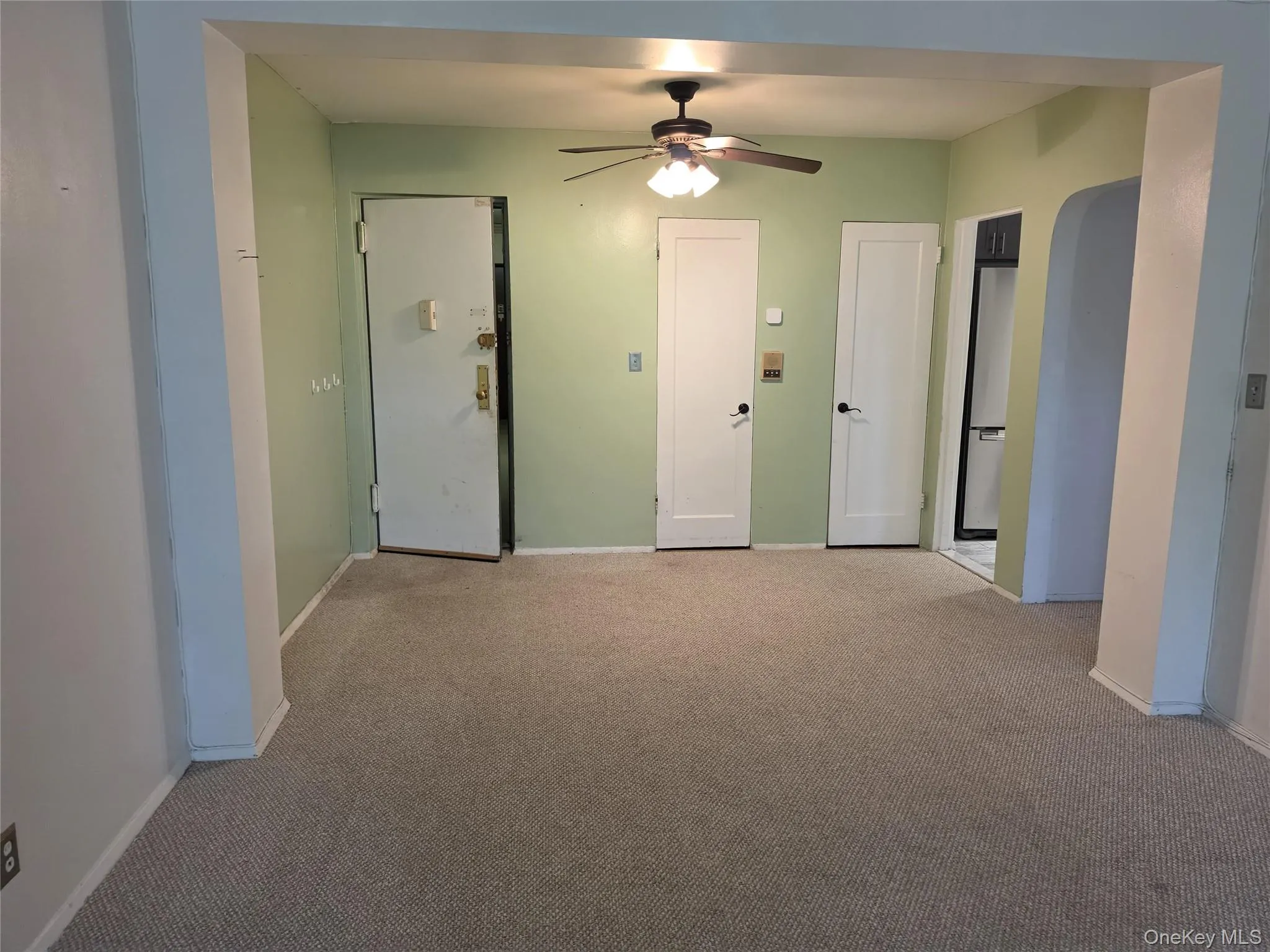 Carpeted room featuring light green walls, a ceiling fan with light fixture, and white trim Carpeted room featuring light green walls, a ceiling fan with light fixture, and white trim