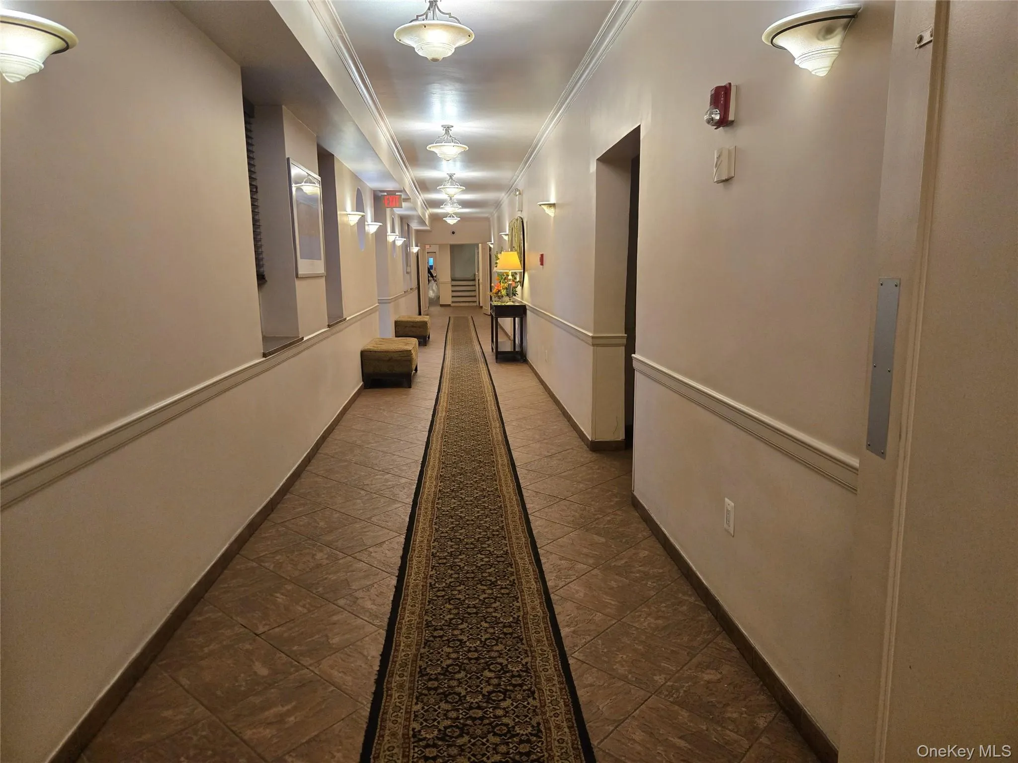 Long hallway featuring extensive tile flooring with an ornate runner Long hallway featuring extensive tile flooring with an ornate runner