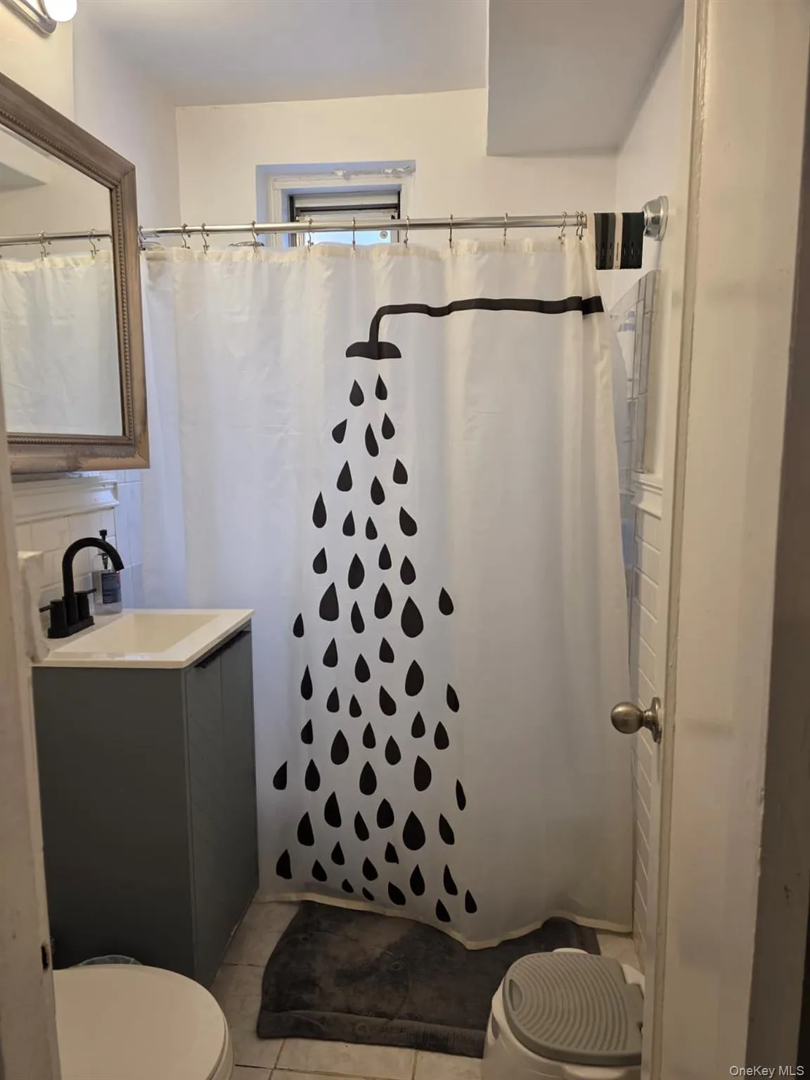 Bathroom with a white tiled shower surround and a window Bathroom with a white tiled shower surround and a window