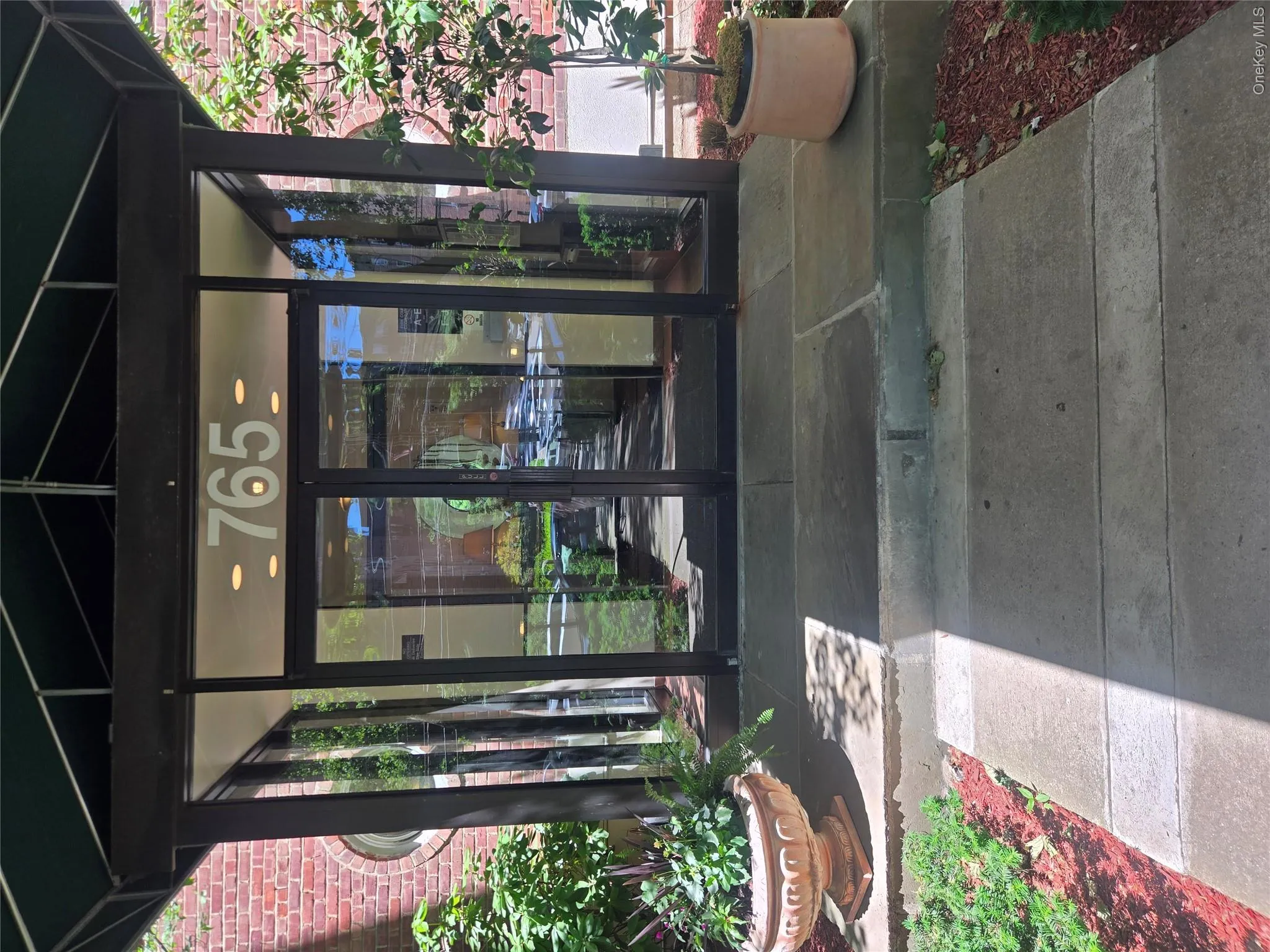 Building entrance featuring a dark green awning, glass double doors, and a stone walkway Building entrance featuring a dark green awning, glass double doors, and a stone walkway