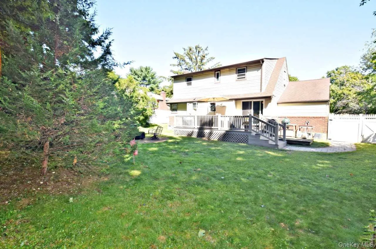 Expansive backyard with a manicured lawn, multi-level deck, and mature privacy plantings Expansive backyard with a manicured lawn, multi-level deck, and mature privacy plantings