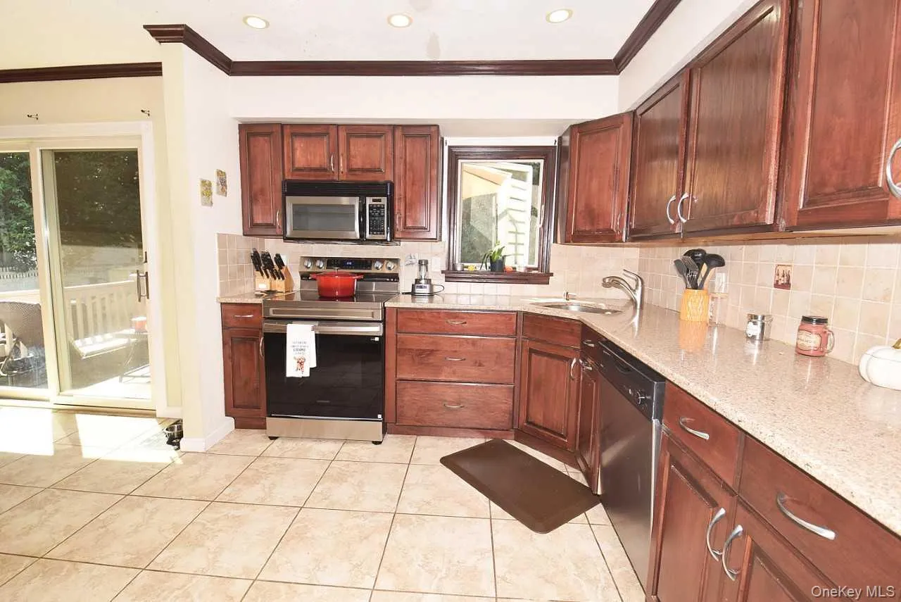 Kitchen featuring abundant wood cabinetry, light-toned countertops, stainless steel appliances, and tiled flooring Kitchen featuring abundant wood cabinetry, light-toned countertops, stainless steel appliances, and tiled flooring